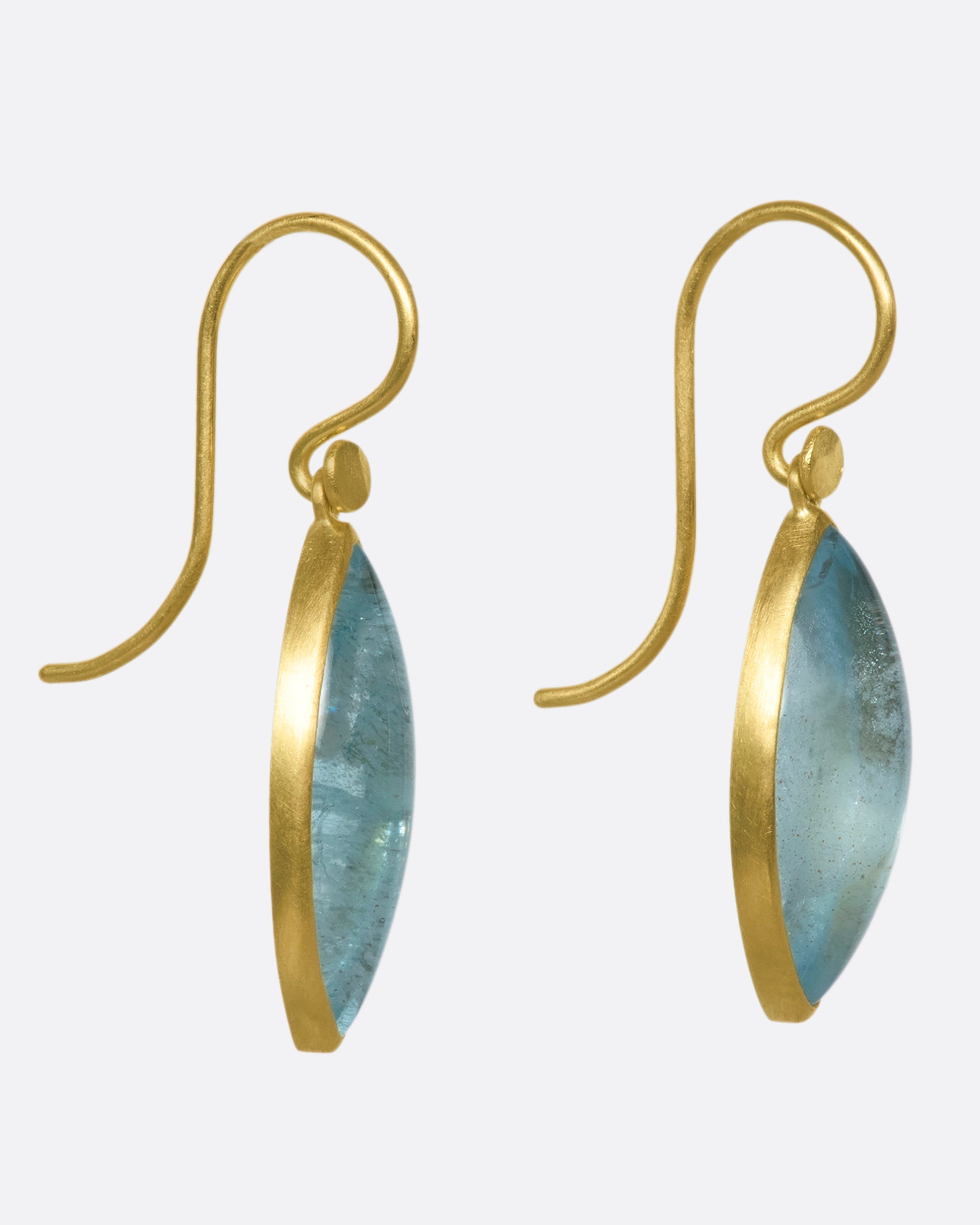 A pair of 18k gold dangling earrings with aquamarine navette drops. These elongated aquamarines contrast with any hair color, making them a versatile and gorgeous pop of color while wearing your hair up or down.