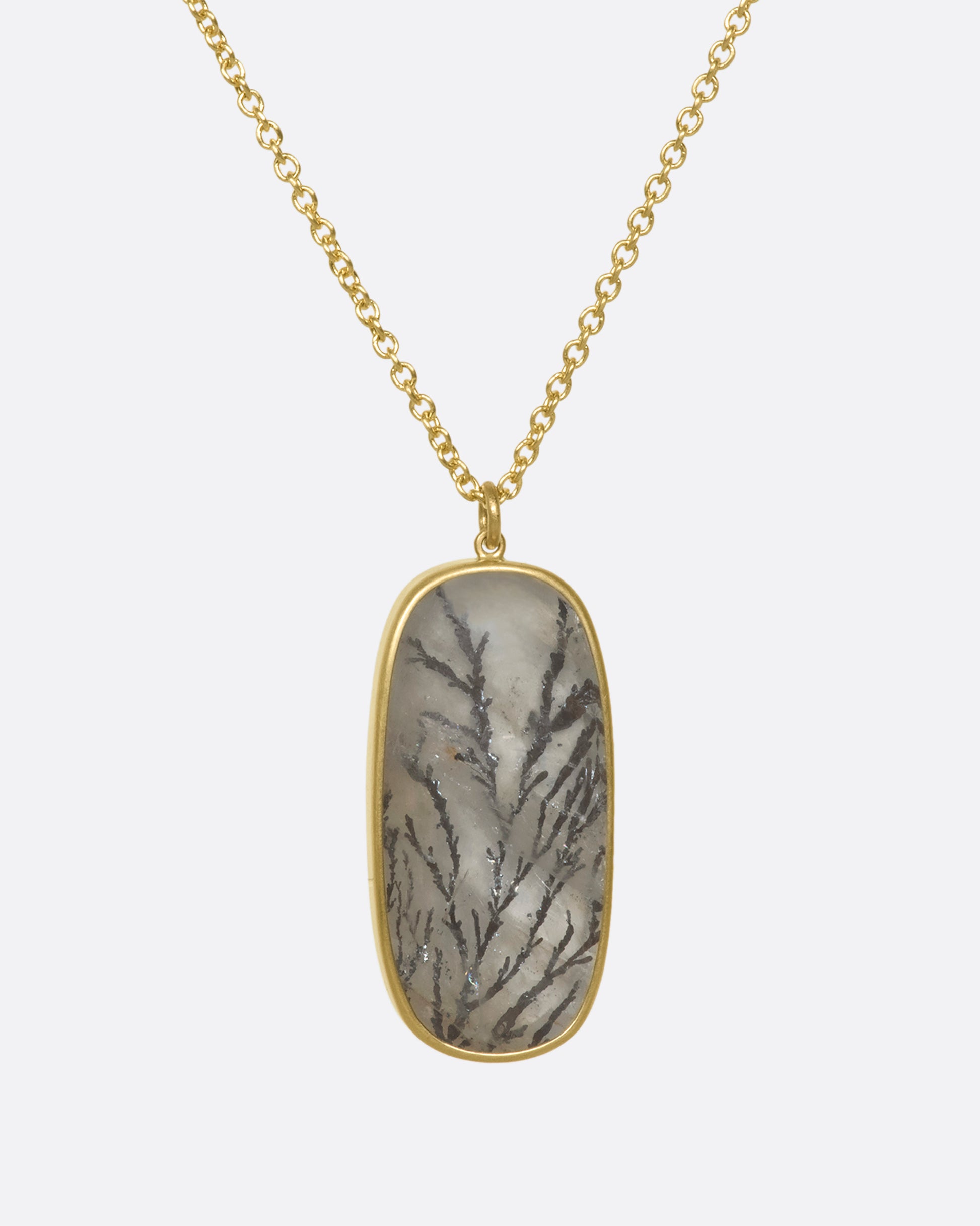 A hanging dendritic quartz pendant on a yellow gold chain.