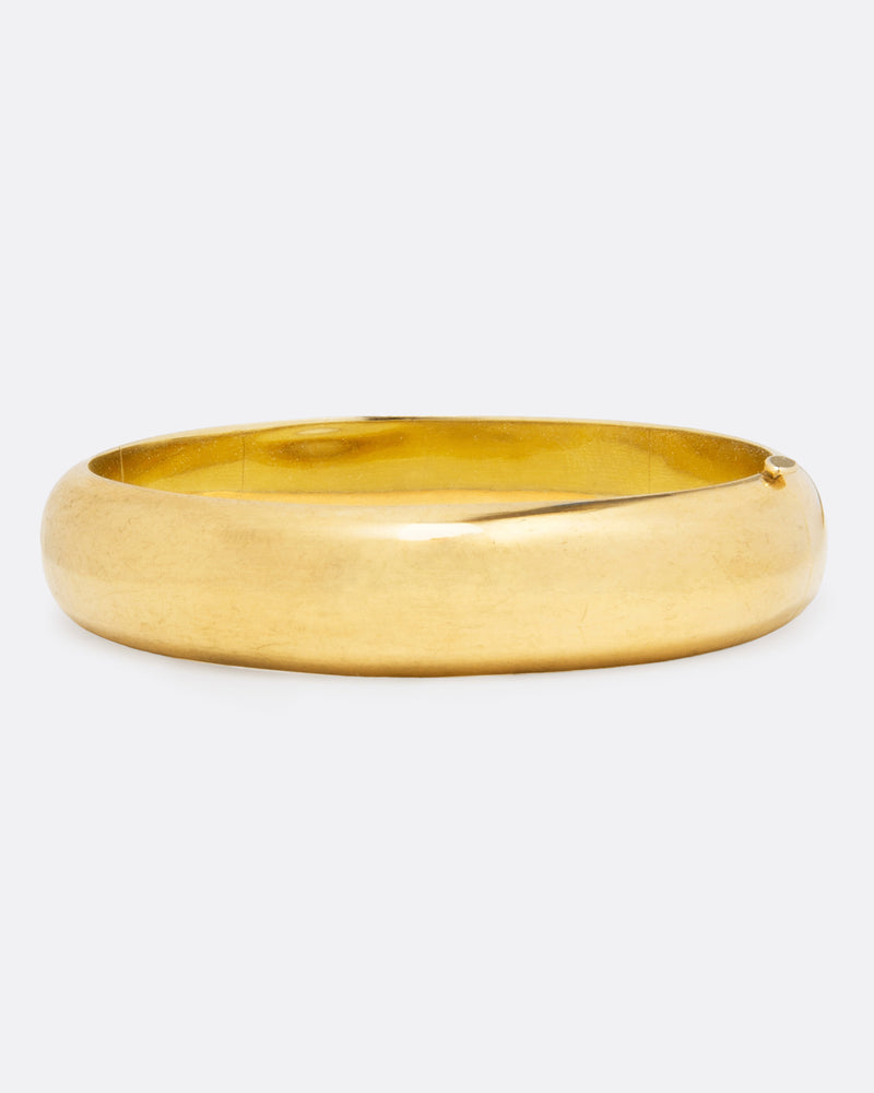 Vintage rounded cuff bracelet in 14k yellow gold, a wide polished hinged bangle with a seamless closure