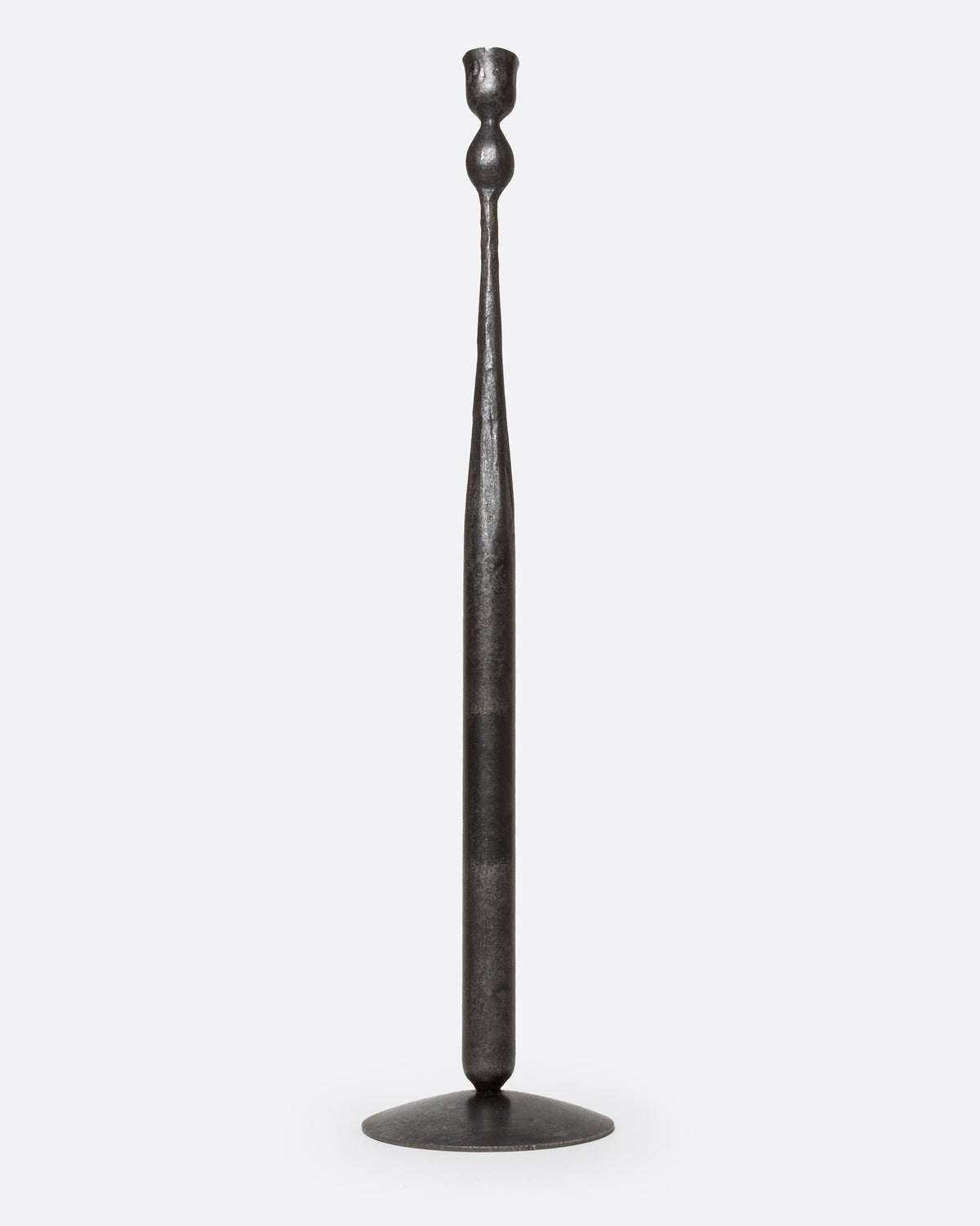 A tall, slender iron candlestick holder with  a flared circular base, shown from the front.
