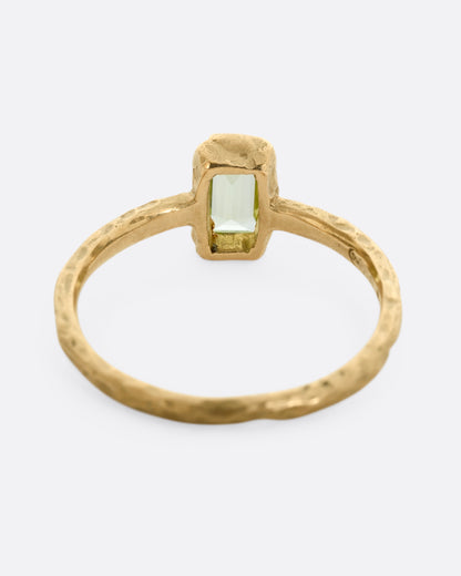 A textured yellow gold ring with a rectangular peridot. Shown from the back.