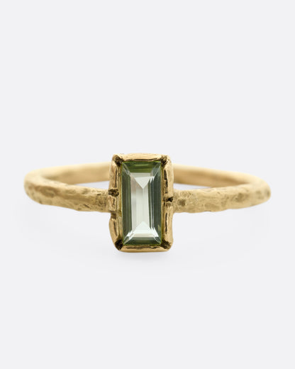 A textured yellow gold ring with a rectangular peridot. Shown from the front.