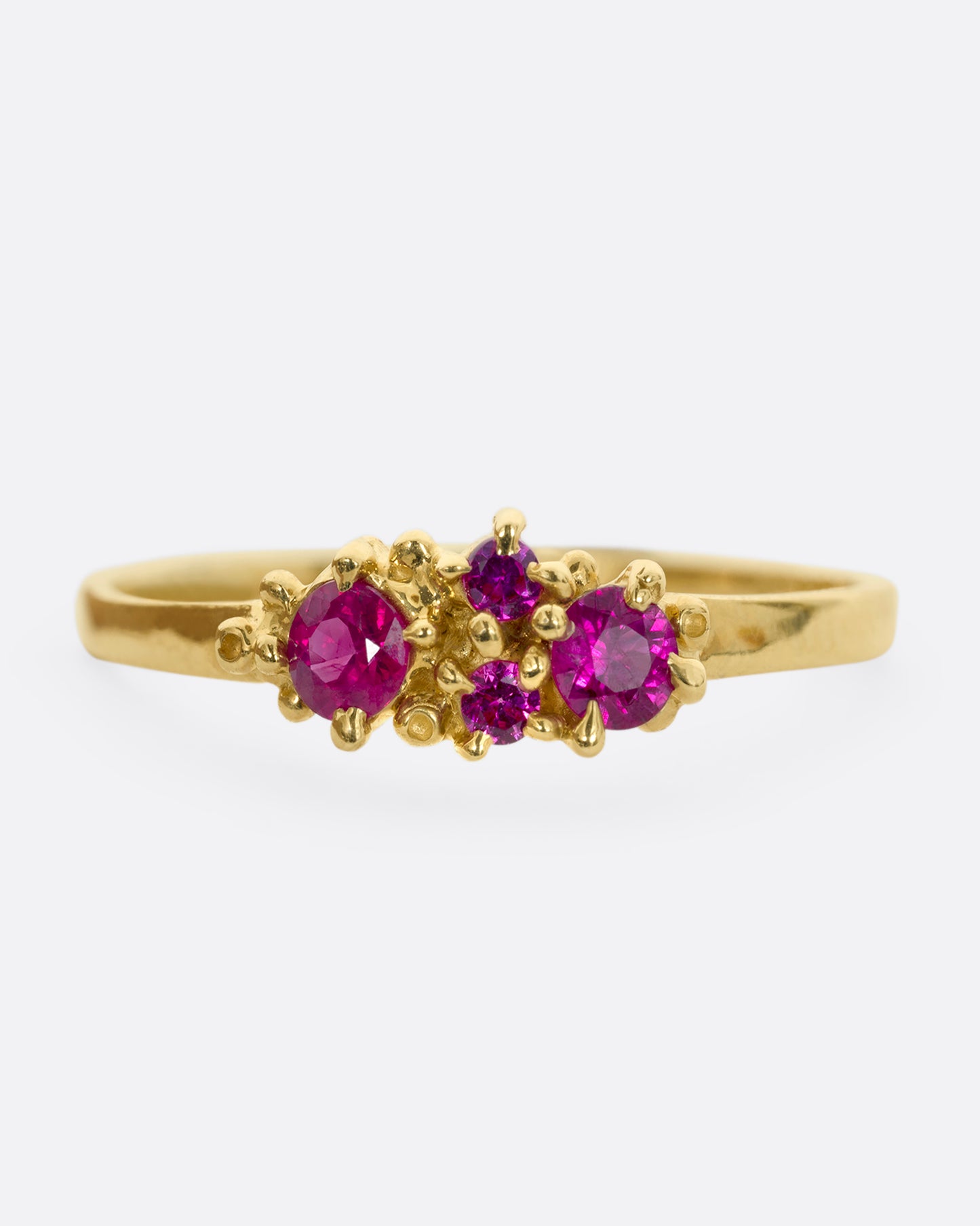 A yellow gold ring with a cluster of four rubies. Shown from the front.