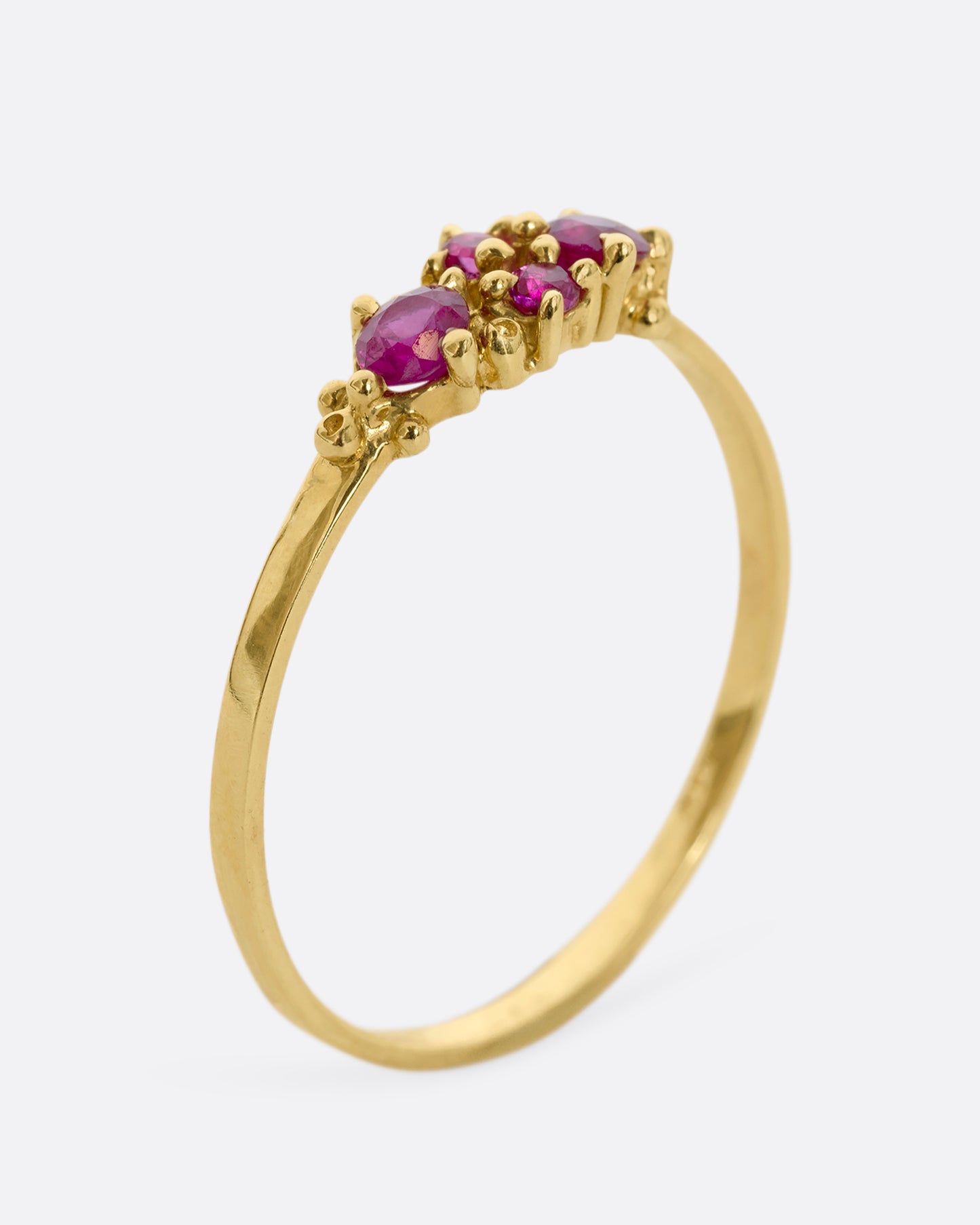 A yellow gold ring with a cluster of four rubies. Shown from the side, standing up.