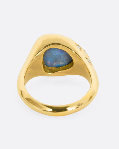 A trillion cut opal in a yellow gold setting with white diamonds on the shoulders. View from the back.