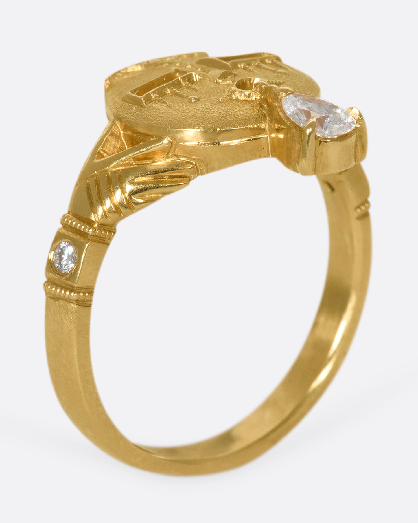 A gold ring with a face and a pear shaped diamond tongue standing upright on its band.
