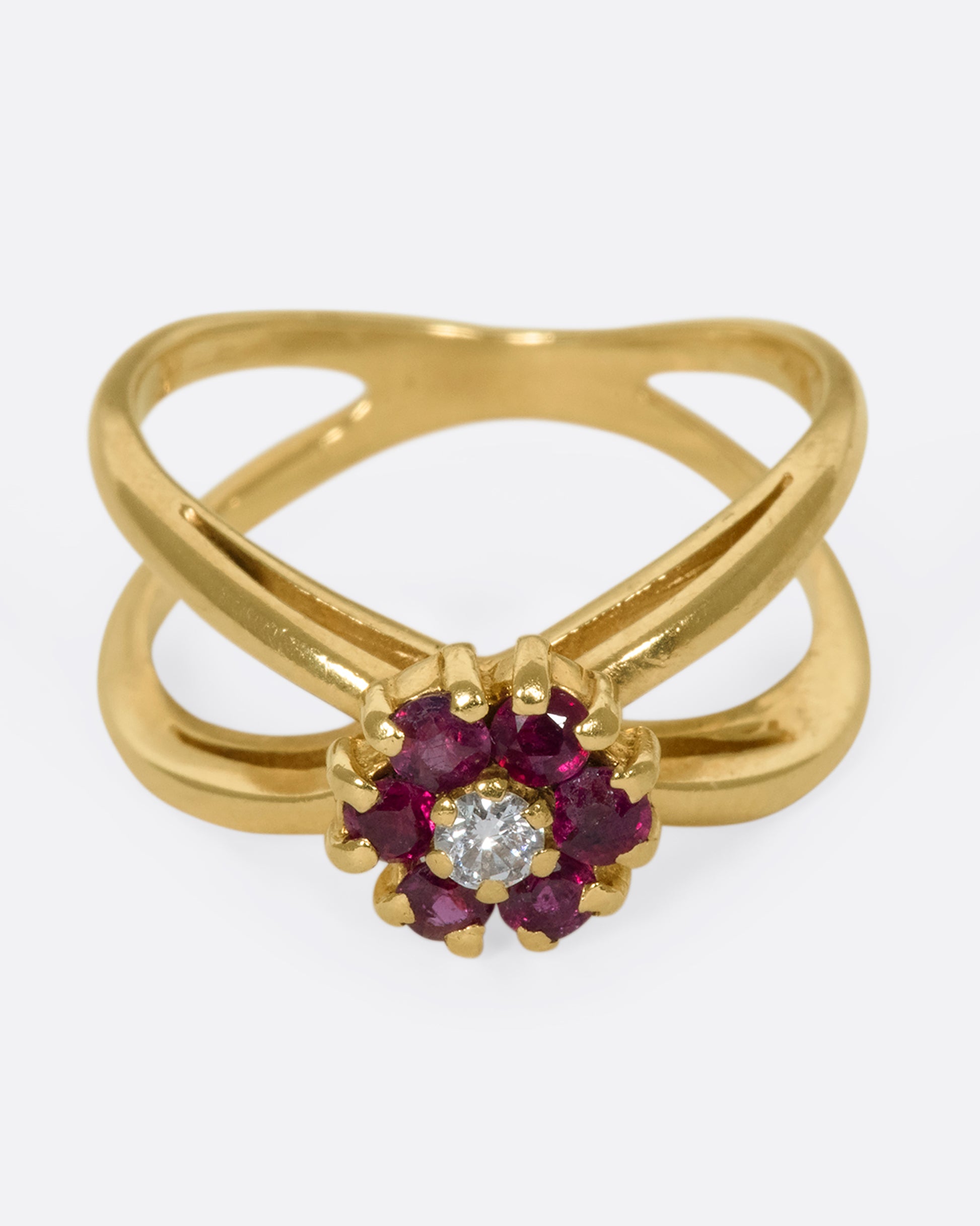 A slightly overhead view of a yellow gold double banded ring with a ruby and diamond flower in the center.