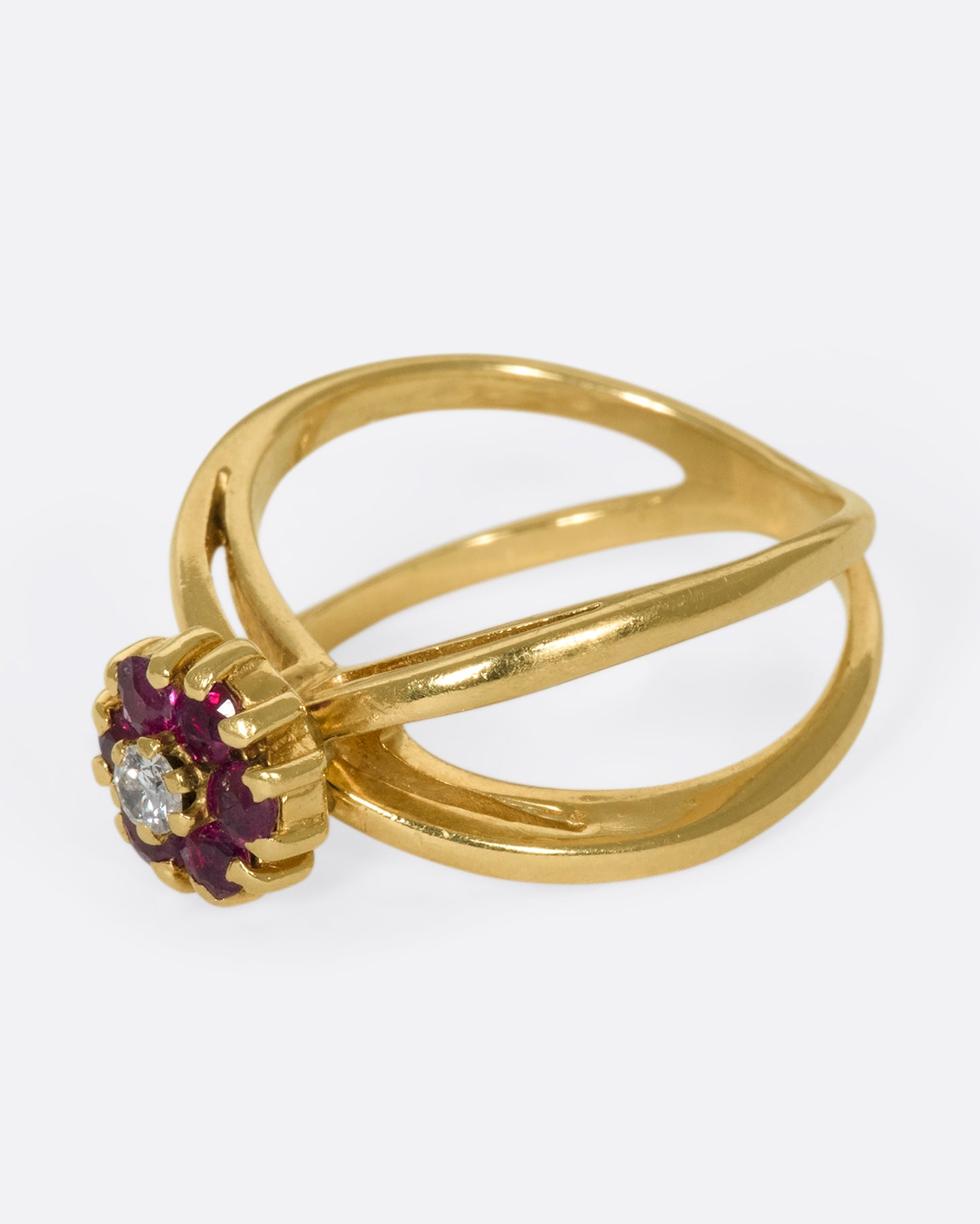 A left side view of a yellow gold double banded ring with a ruby and diamond flower in the center.