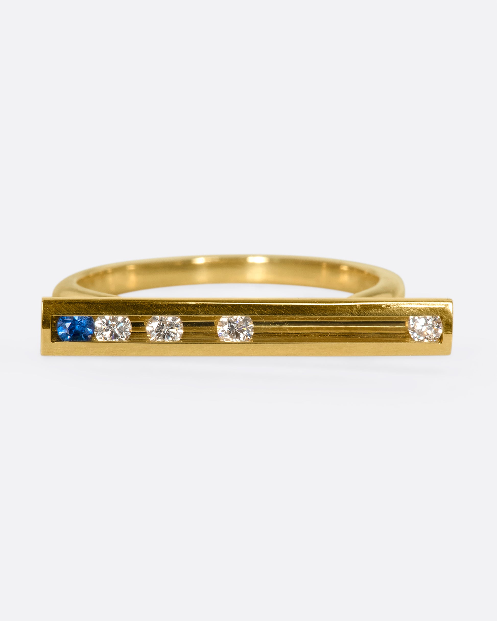 A flat-face ring with blue sapphires and diamonds that glide across an 18K gold bar.