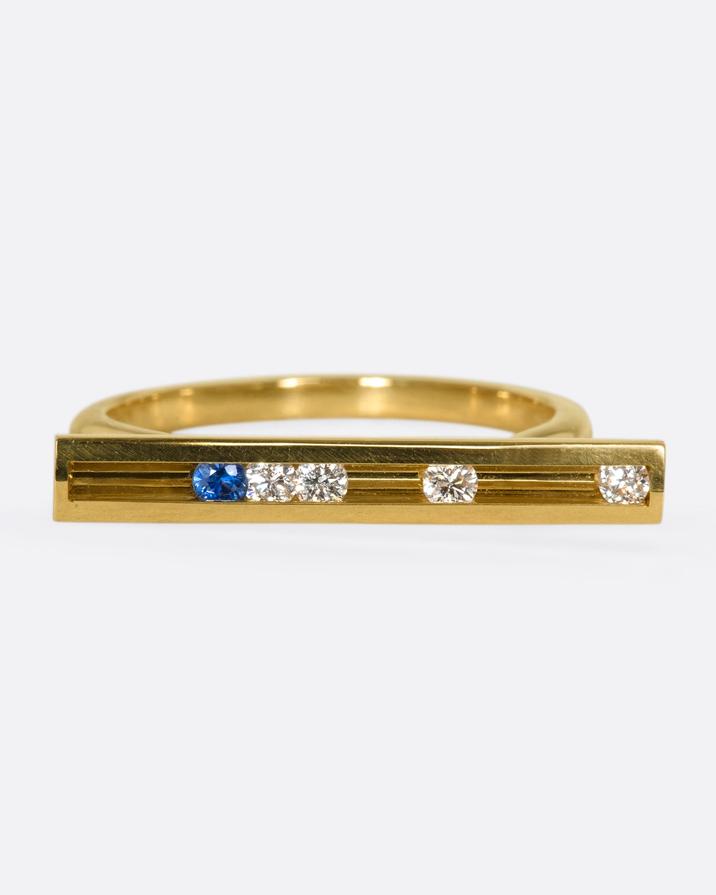 A flat-face ring with blue sapphires and diamonds that glide across an 18K gold bar.