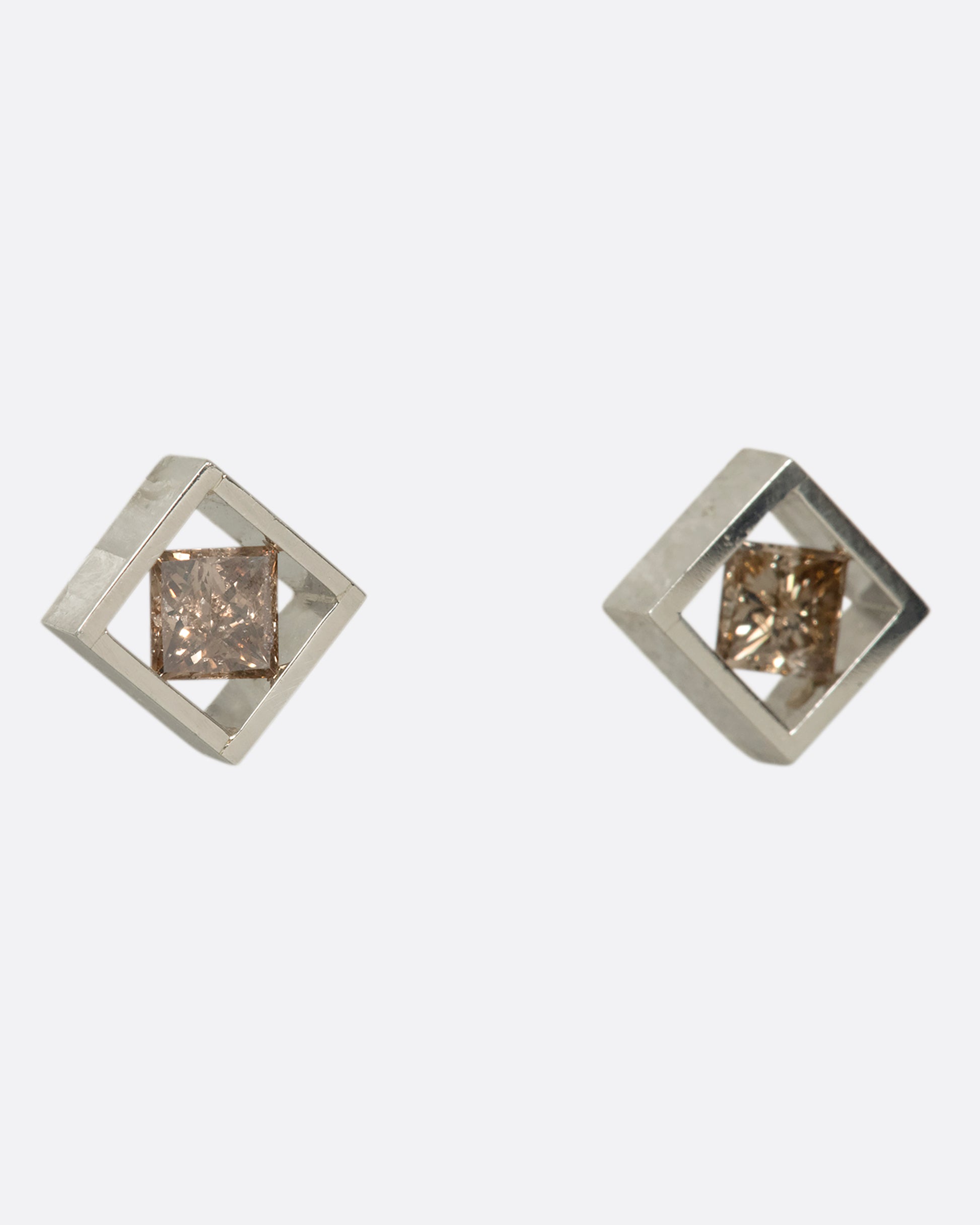 A pair of princess-cut cognac diamonds stretching across a square platinum setting