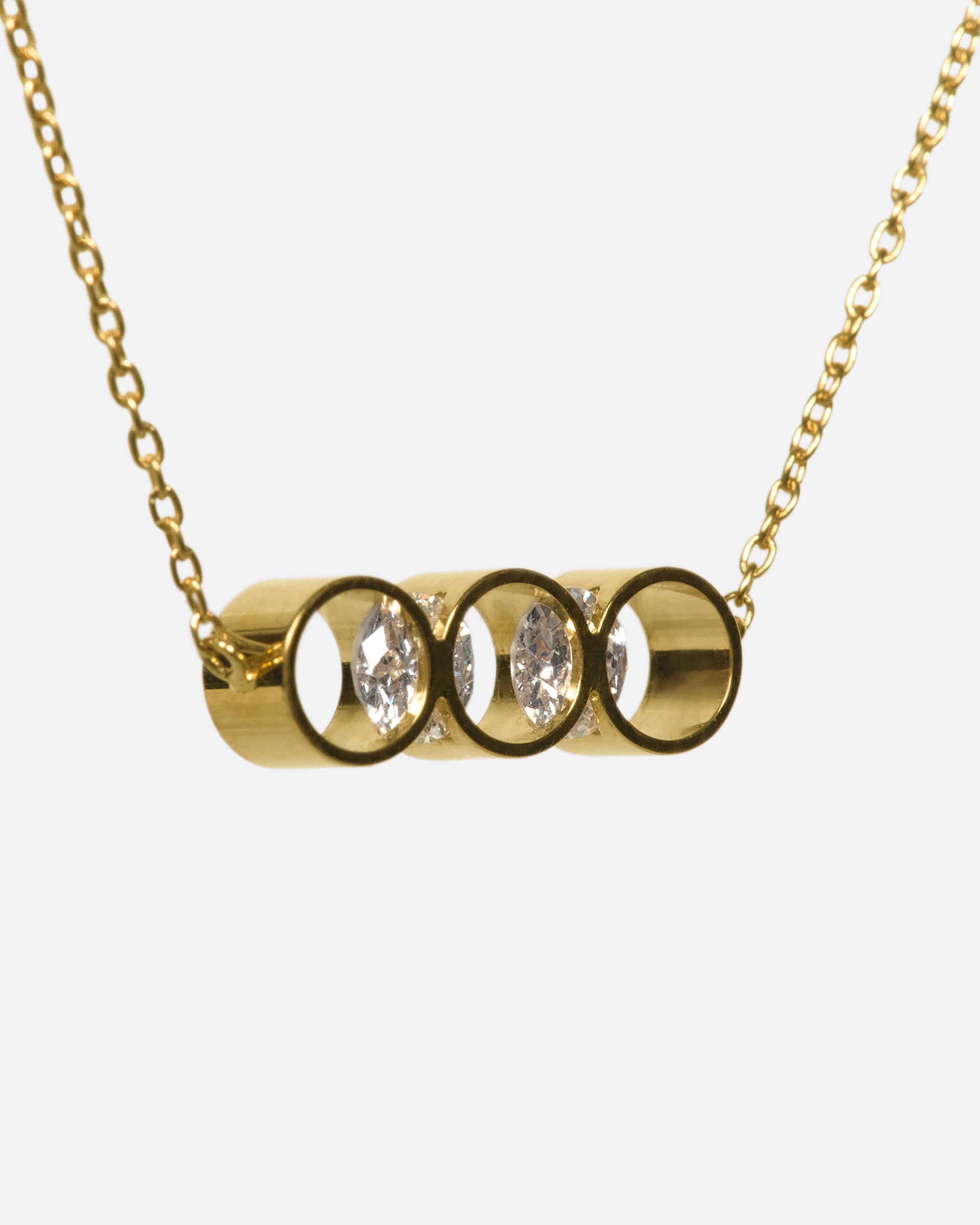 A gold necklace with two diamonds set into circular settings, from the side view.