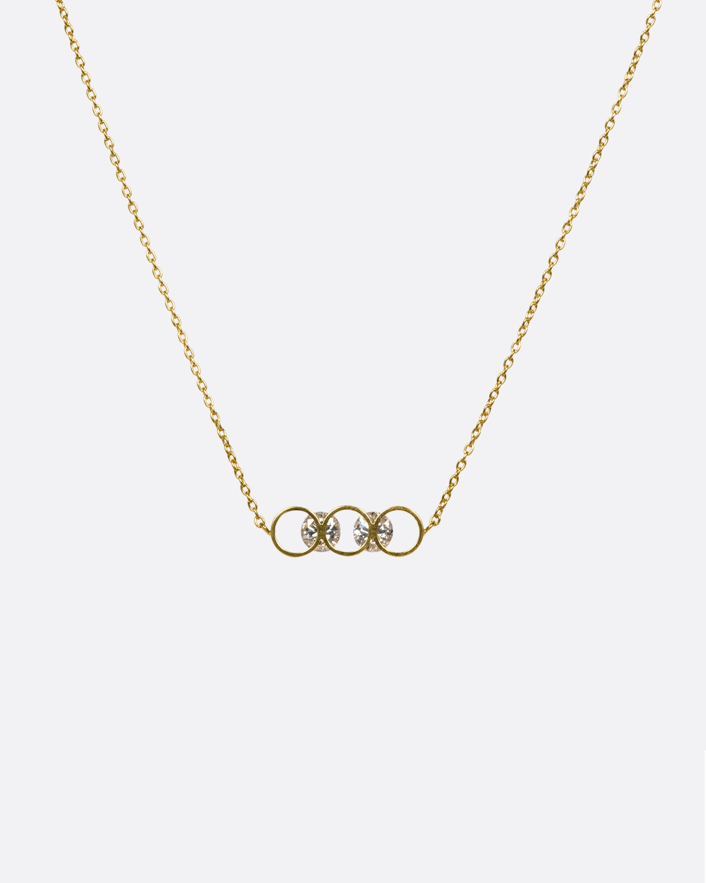 A gold necklace with two diamonds set into circular settings, from far away.