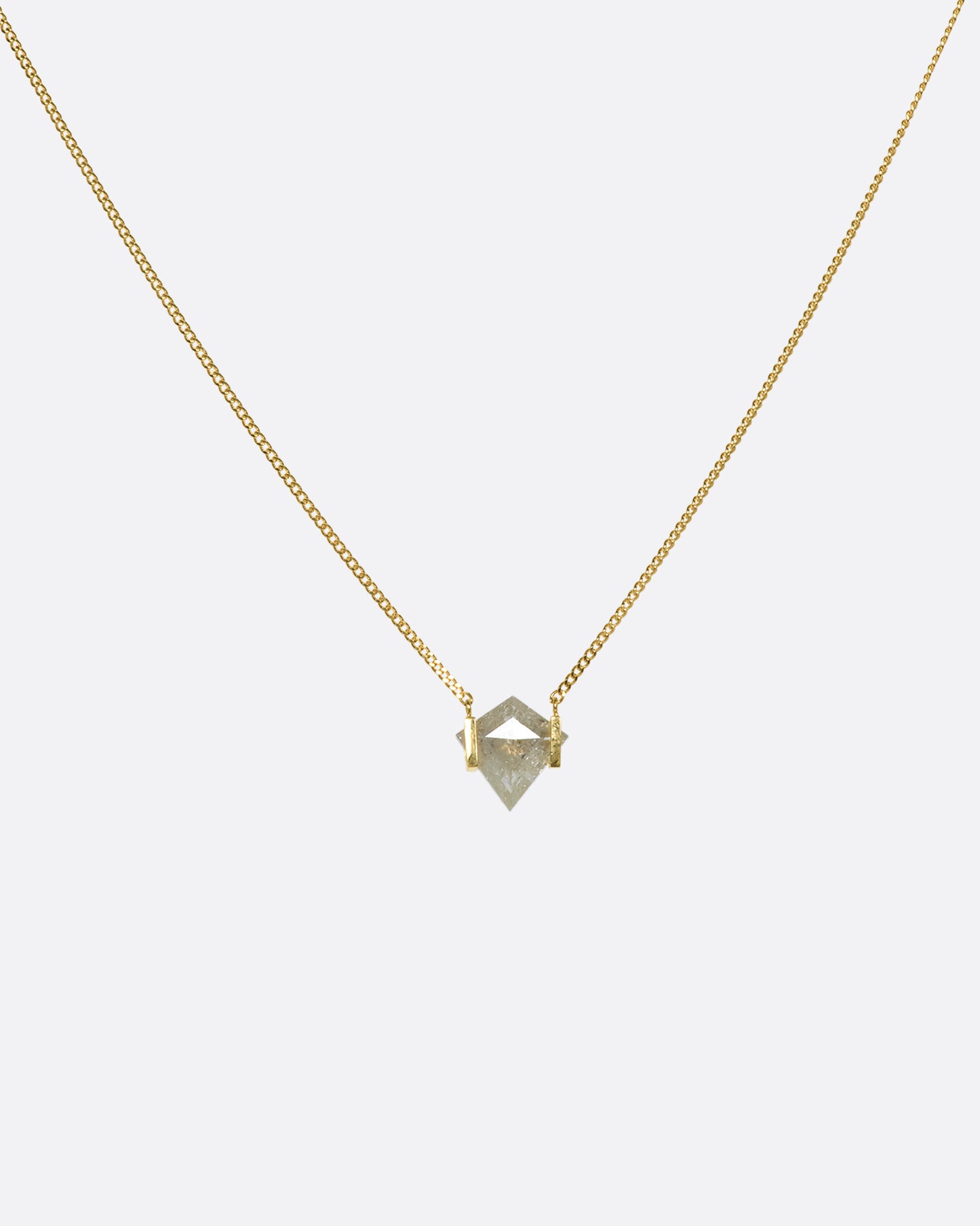 A shield-shaped icy gray diamond suspended between two 18k gold squares