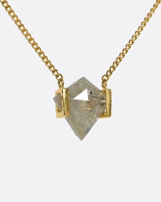 A shield-shaped icy gray diamond suspended between two 18k gold squares