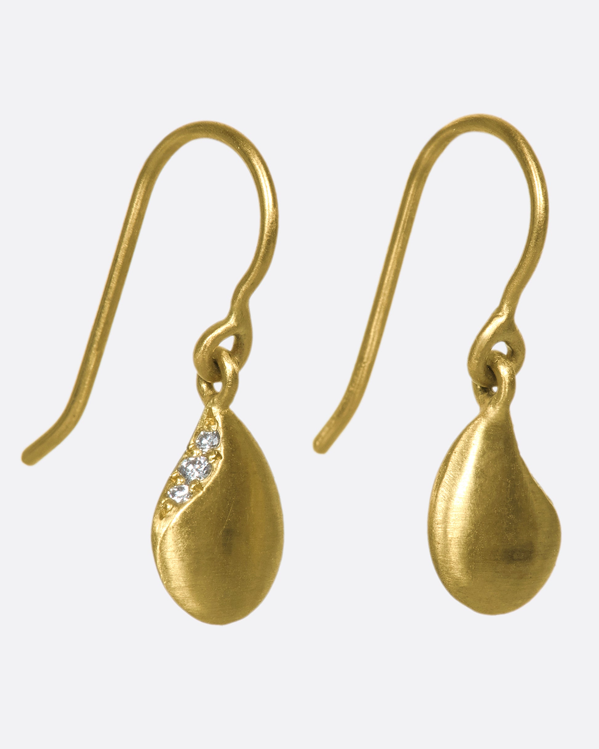 A beautiful pair of 10k gold droplet dangle earrings, etched away to reveal three glittery diamonds.