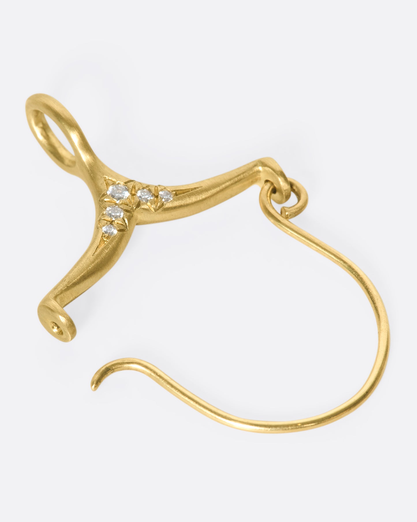 A gold and diamond charm holder laying down and open.