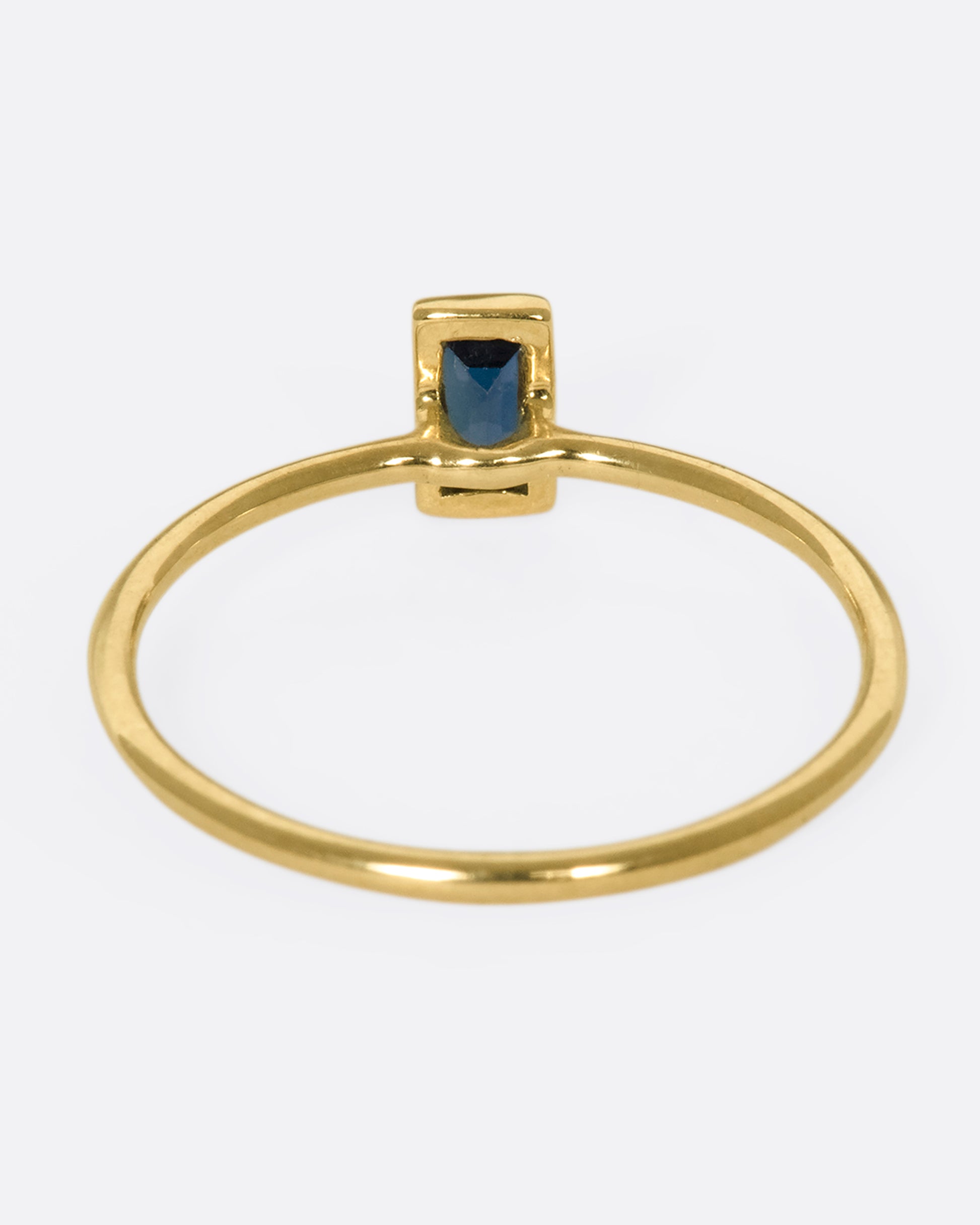 A 9k gold stacking ring with a vertical, bezel-set blue sapphire baguette