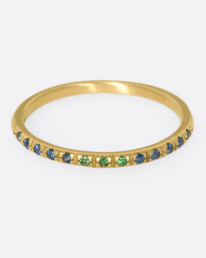 A thin yellow gold band with three green garnets set in the middle and five blue sapphires on either side. Shown from the front.