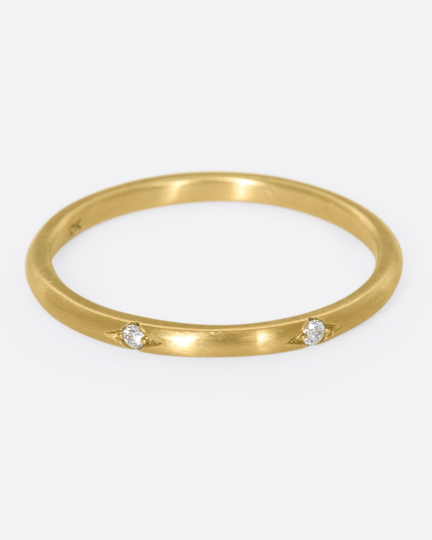 This 10k gold stacking ring features two flush-set white diamonds that sink into the soft gold band