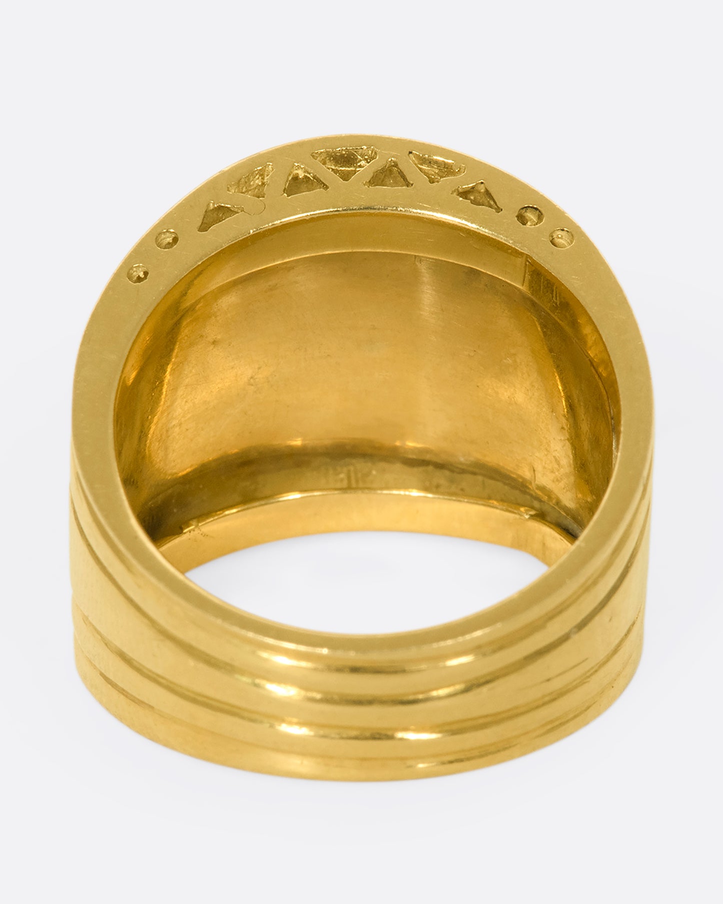 A view of the underside view of a wide, tapered yellow gold ring with mother of pearl and lapis inlaid stripes.