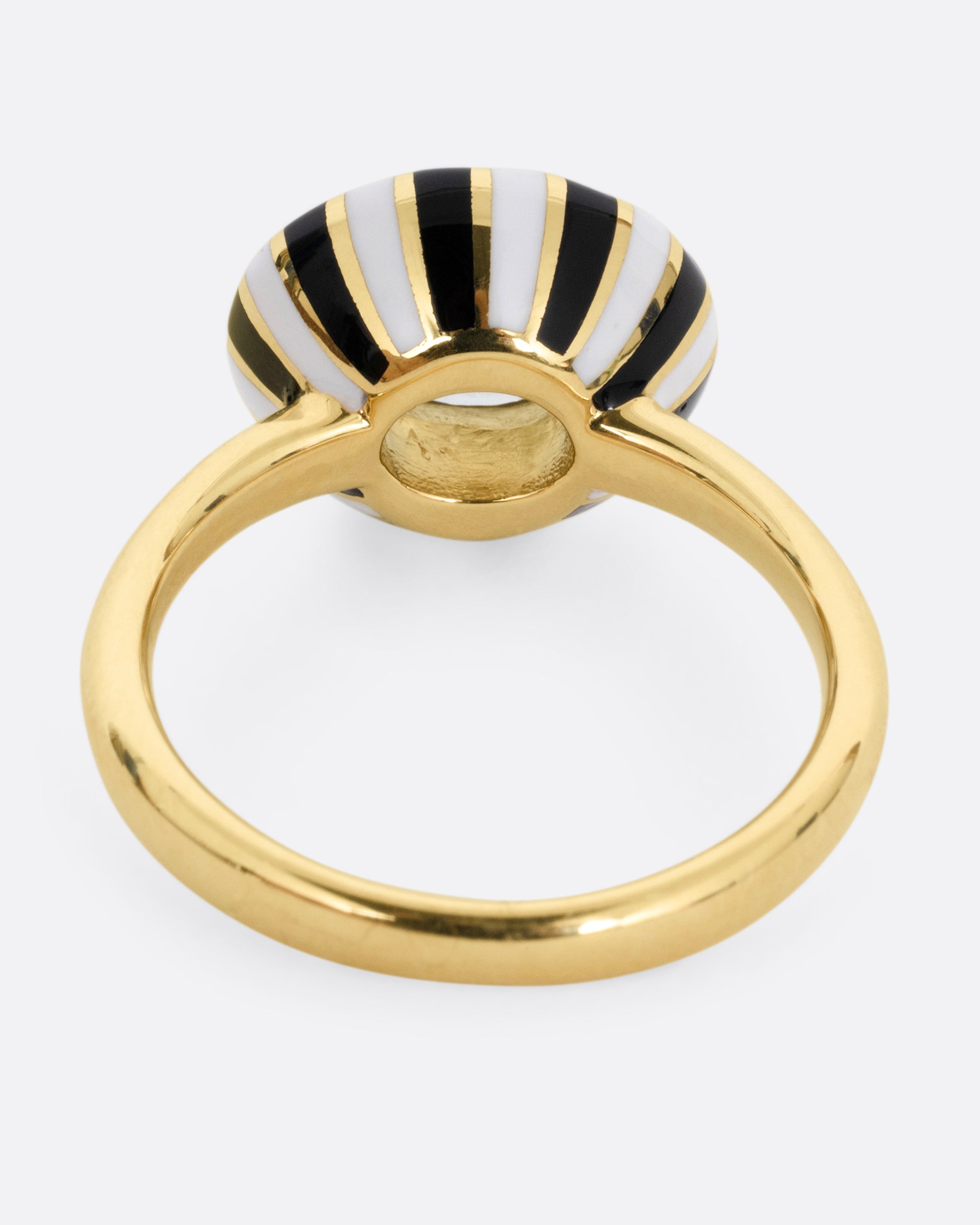 A yellow gold ring with an enamel checkerboard pattern around a green sapphire, shown from the back.