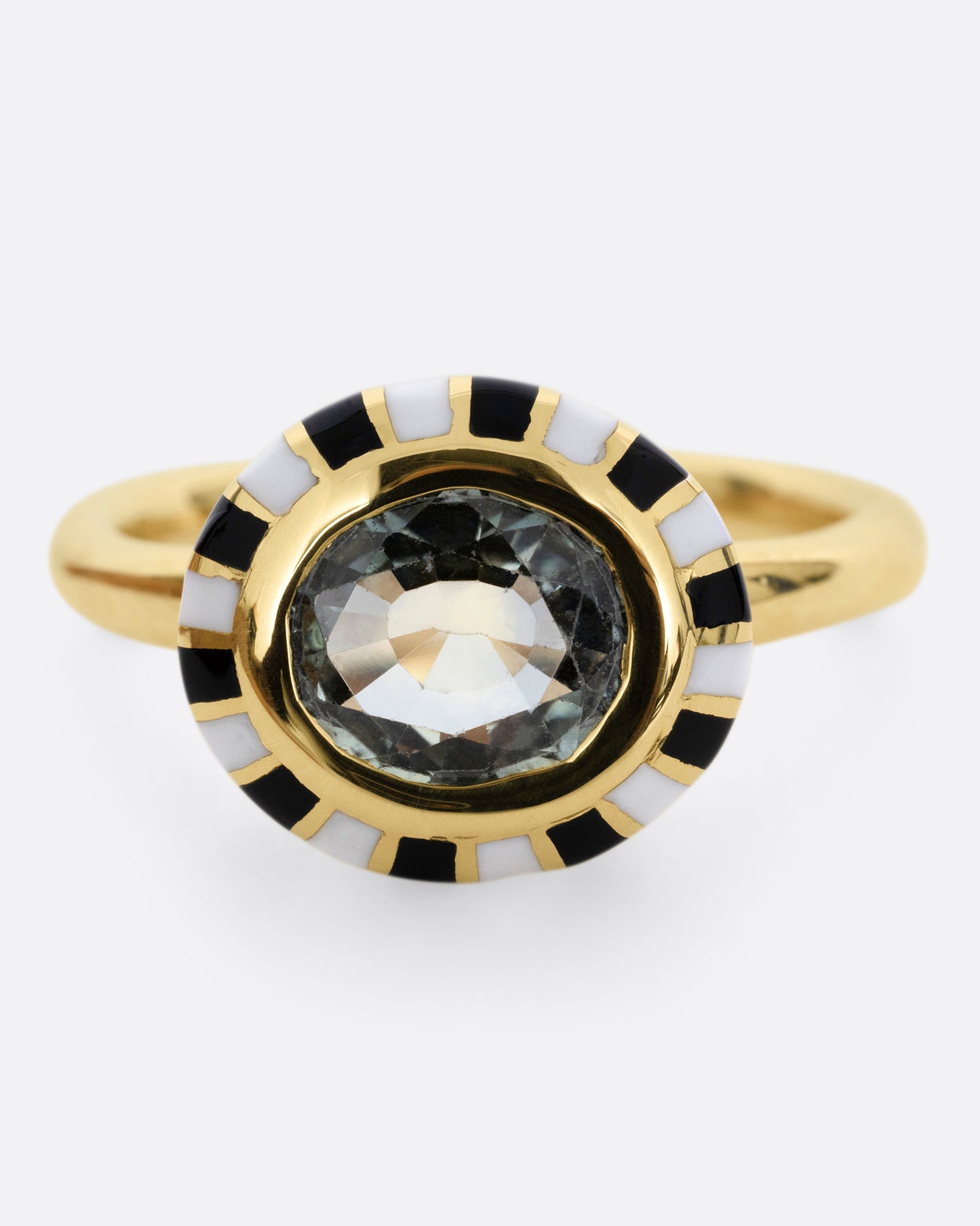 A yellow gold ring with an enamel checkerboard pattern around a green sapphire, shown from the front.