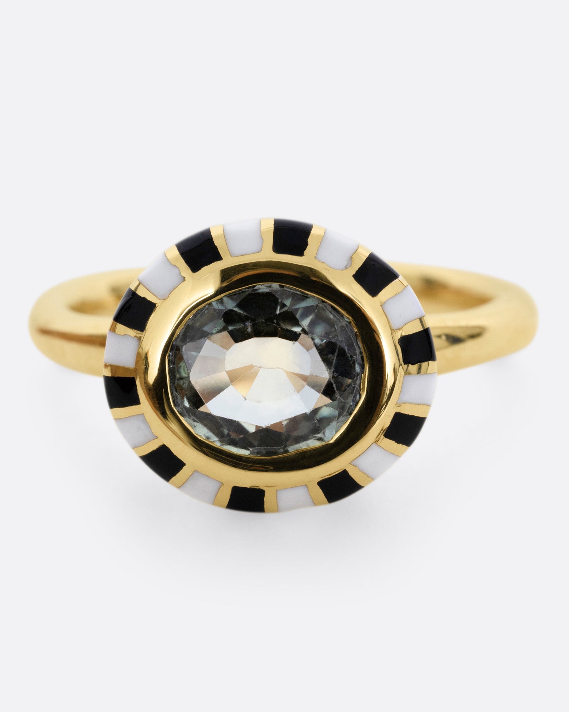 A yellow gold ring with an enamel checkerboard pattern around a green sapphire, shown from the front.