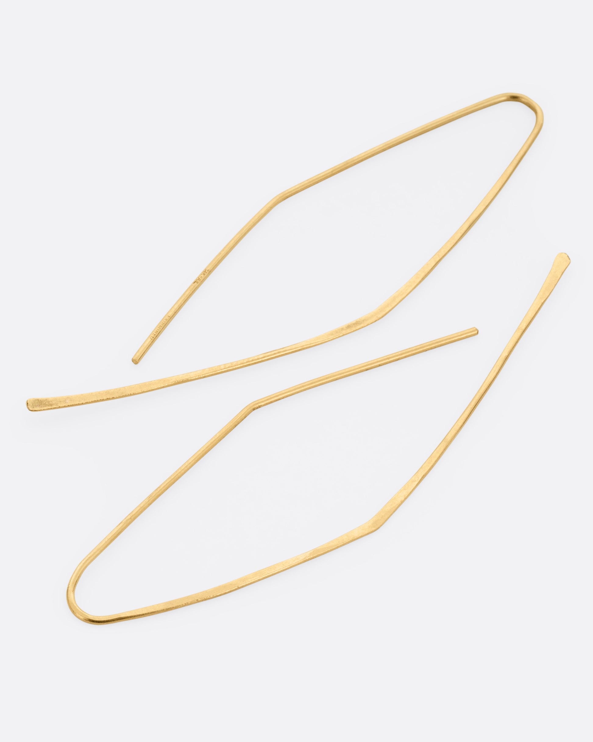 A pair of yellow gold angular hammered hook earrings. Shown lying flat from the side.
