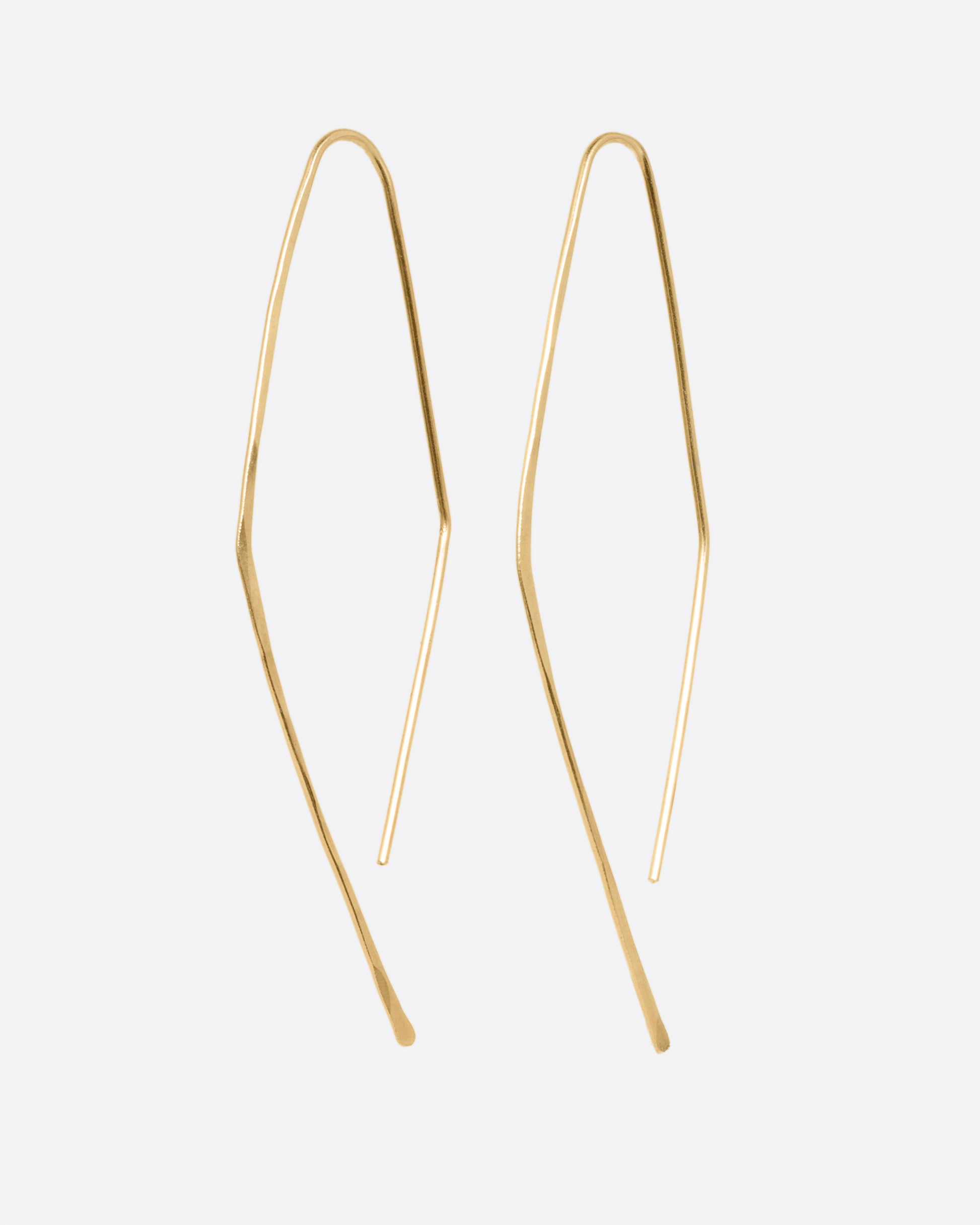 A pair of yellow gold angular hammered hook earrings. Shown from the side.