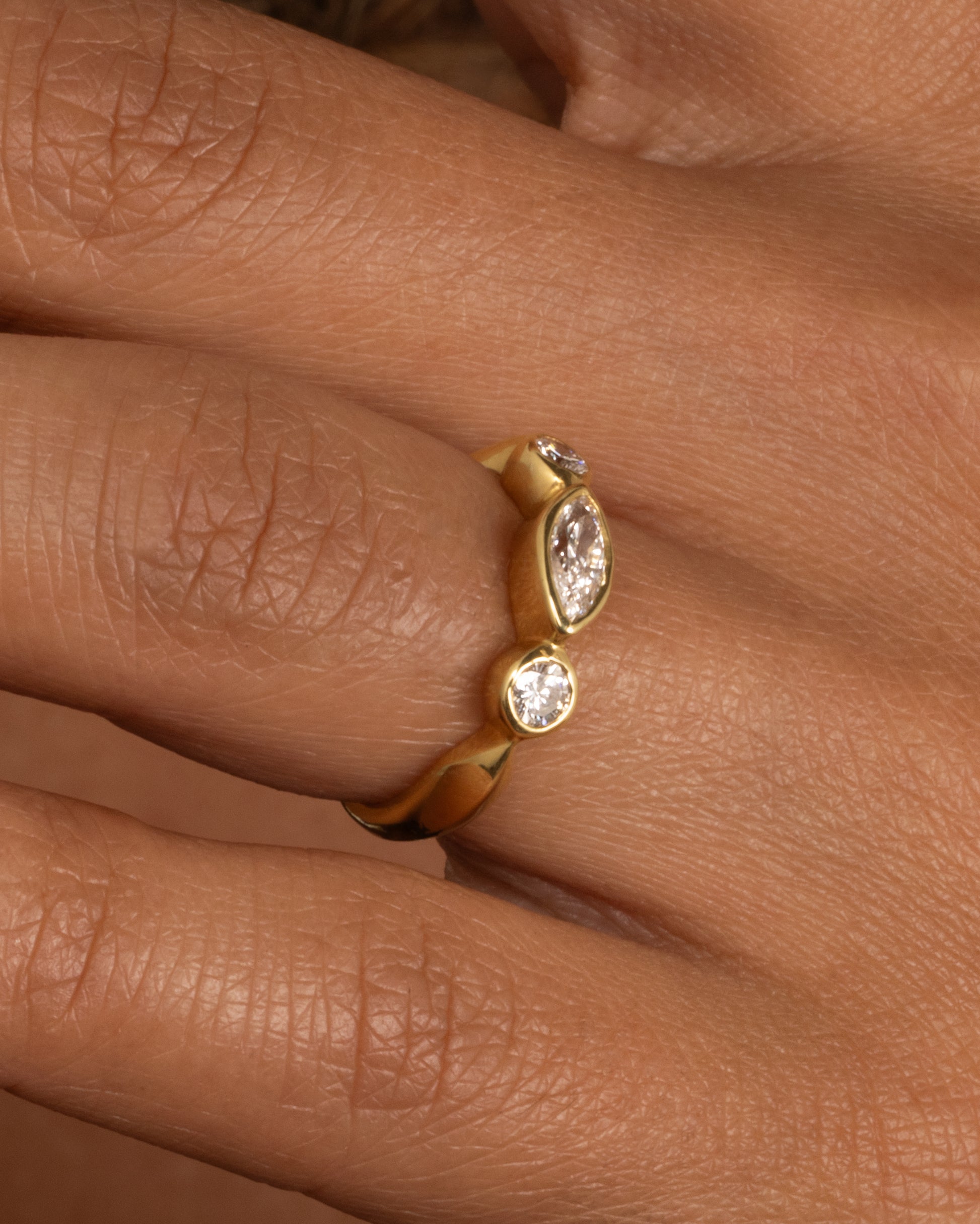 A yellow gold ring with three diamonds shown worn.