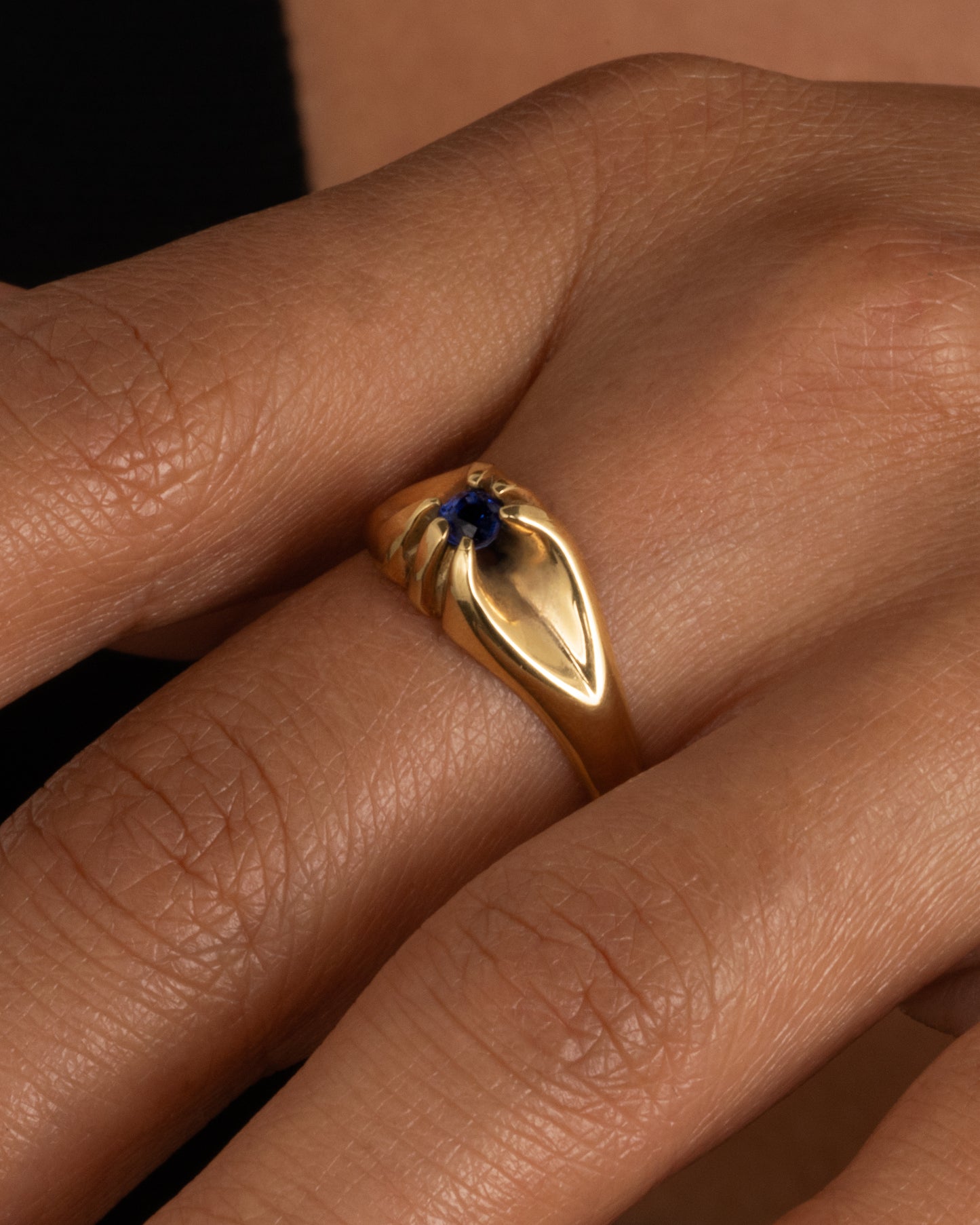 A yellow gold ring with a prong set blue sapphire. Shown worn