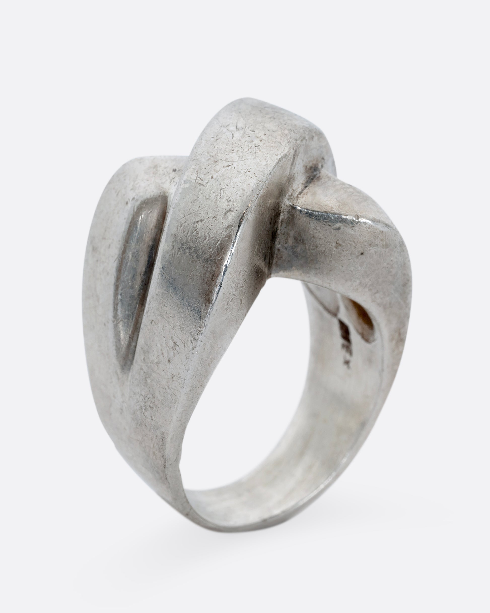 A sterling silver ring that criss crosses in the front. Shown from the side standing up.