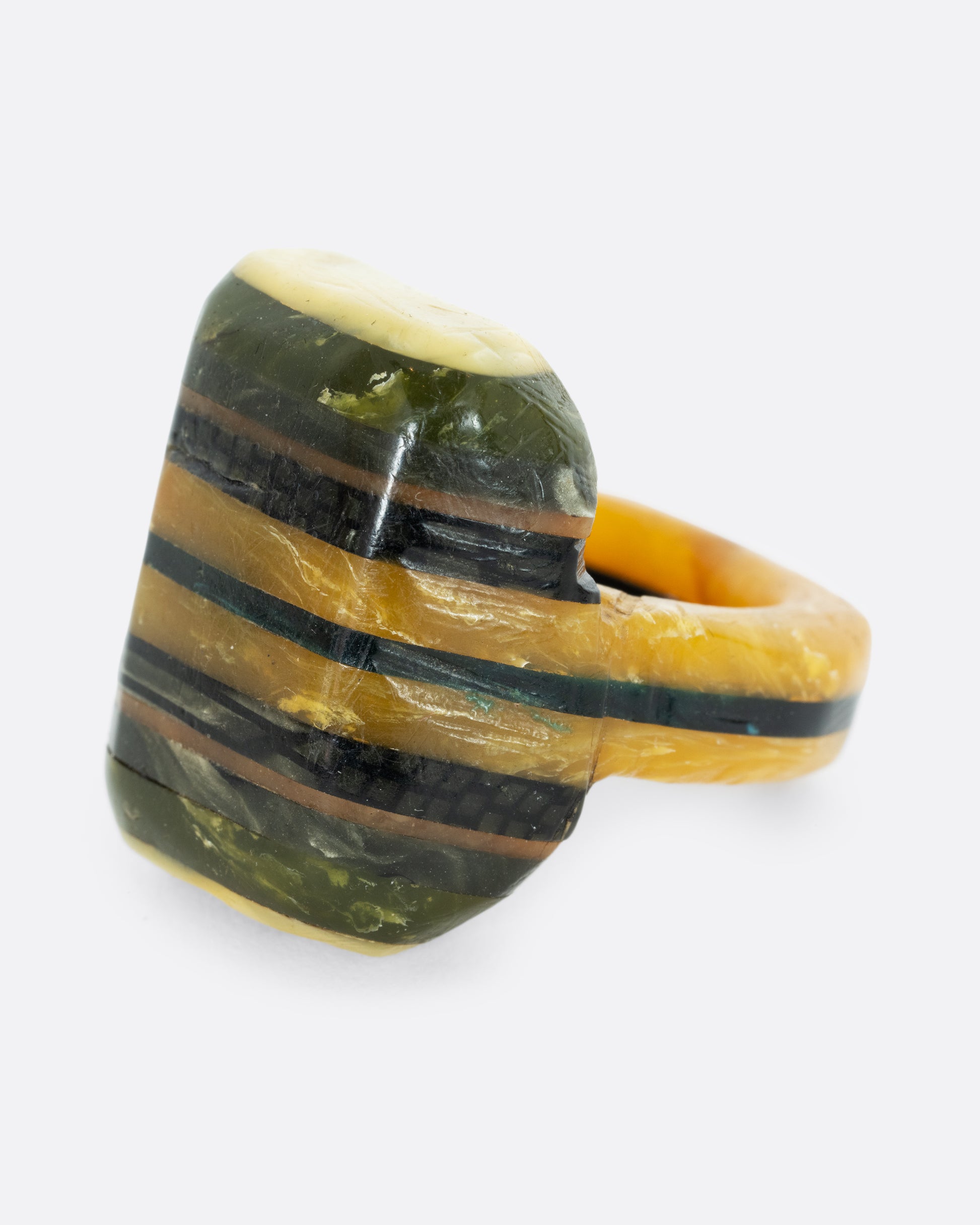 A green black and yellow composite celluloid prison art ring. Shown from the side.