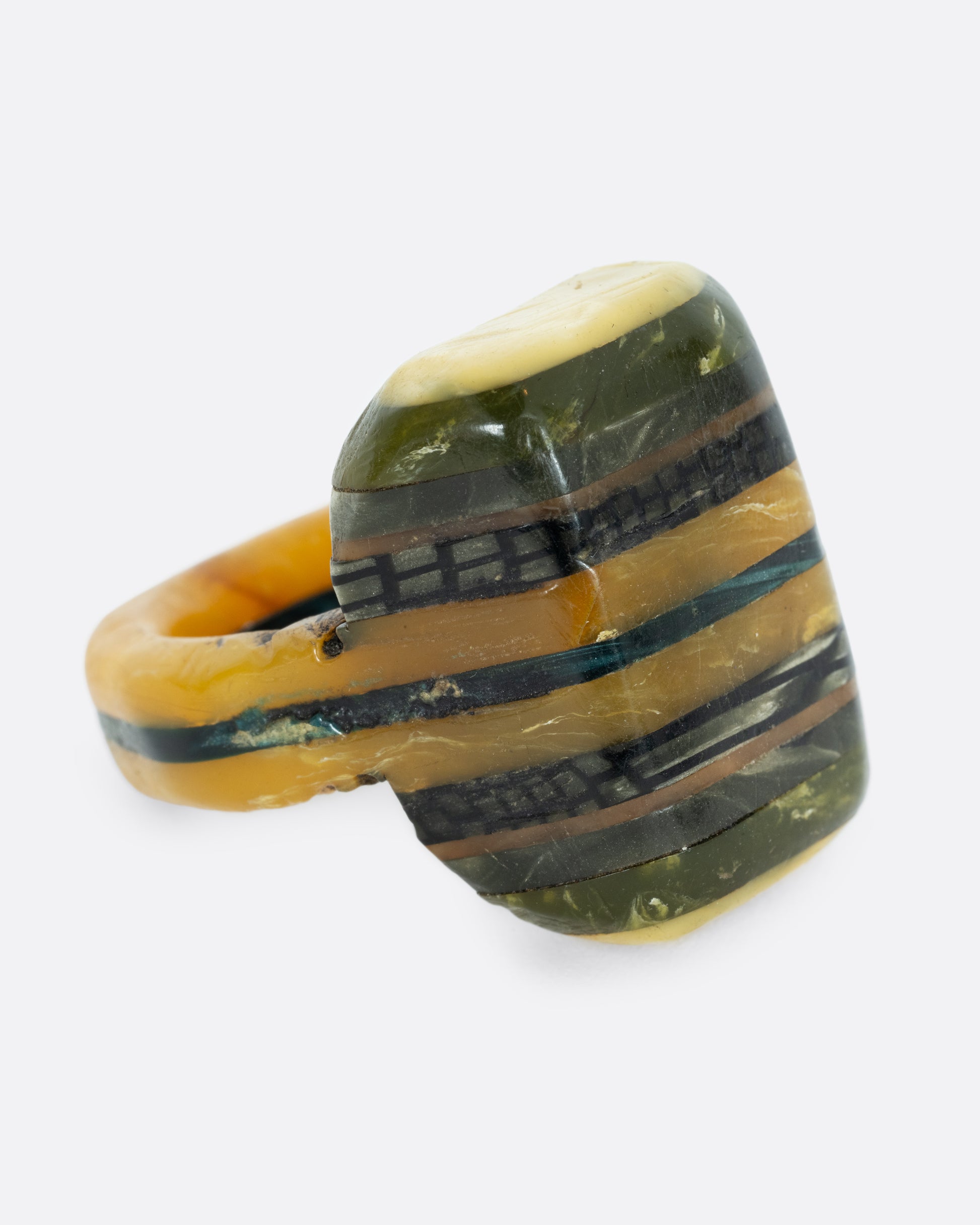 A green black and yellow composite celluloid prison art ring. Shown from the side.