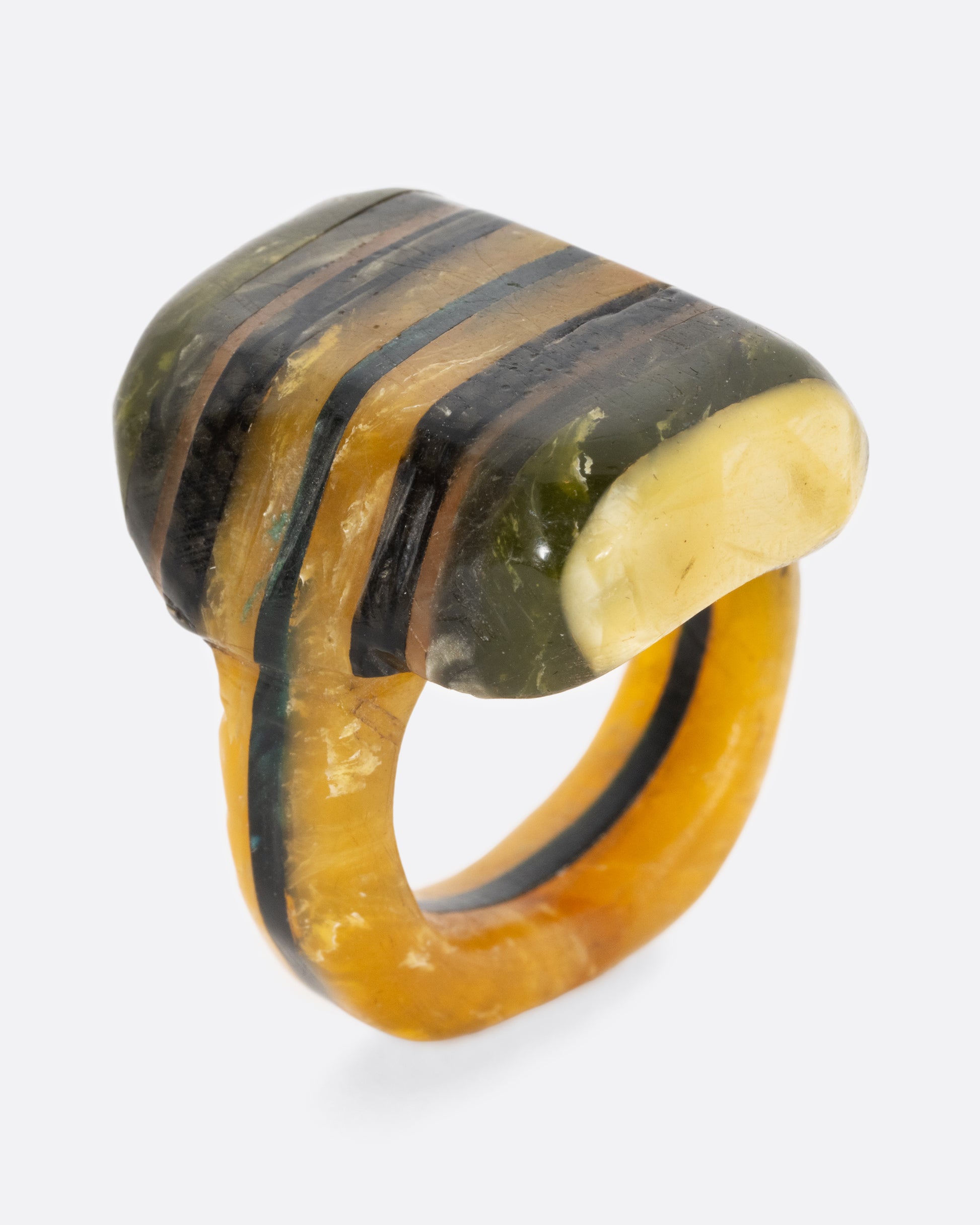 A green black and yellow composite celluloid prison art ring. Shown from the side, standing up.