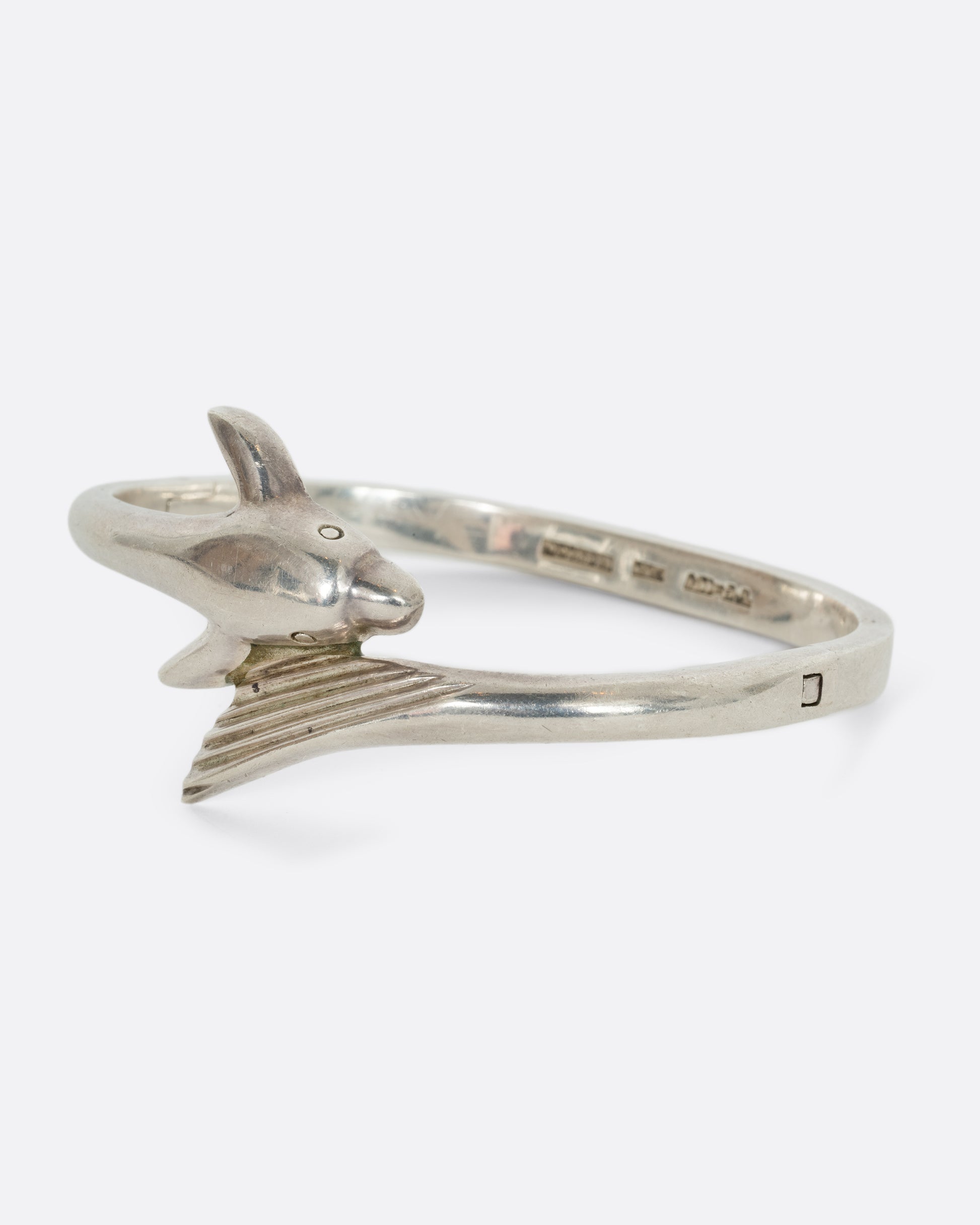 A sterling silver dolphin wrap bracelet. Shown from the side.