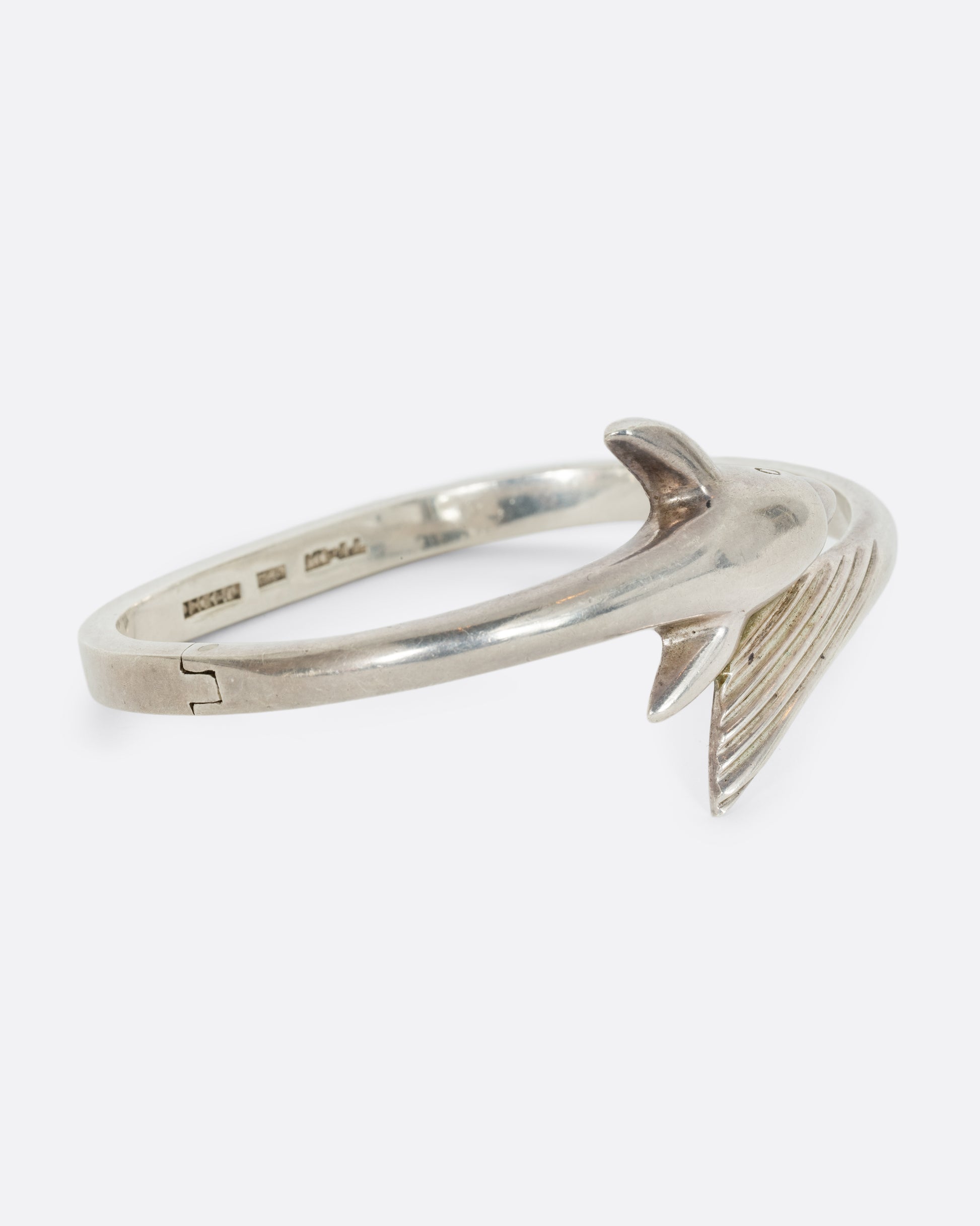 A sterling silver dolphin wrap bracelet. Shown from the side.