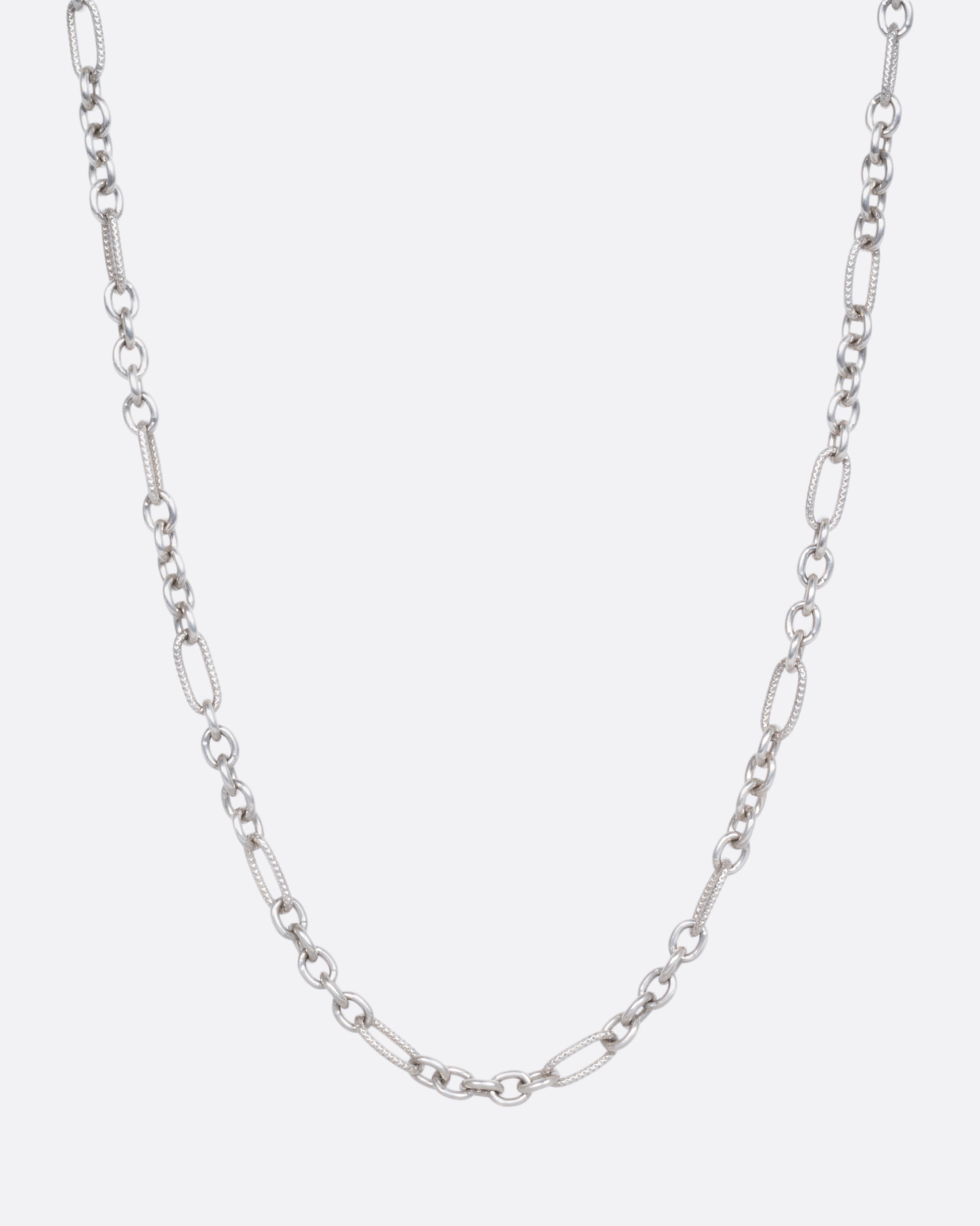 A lengthy textured oval cable chain necklace. View from the front. 