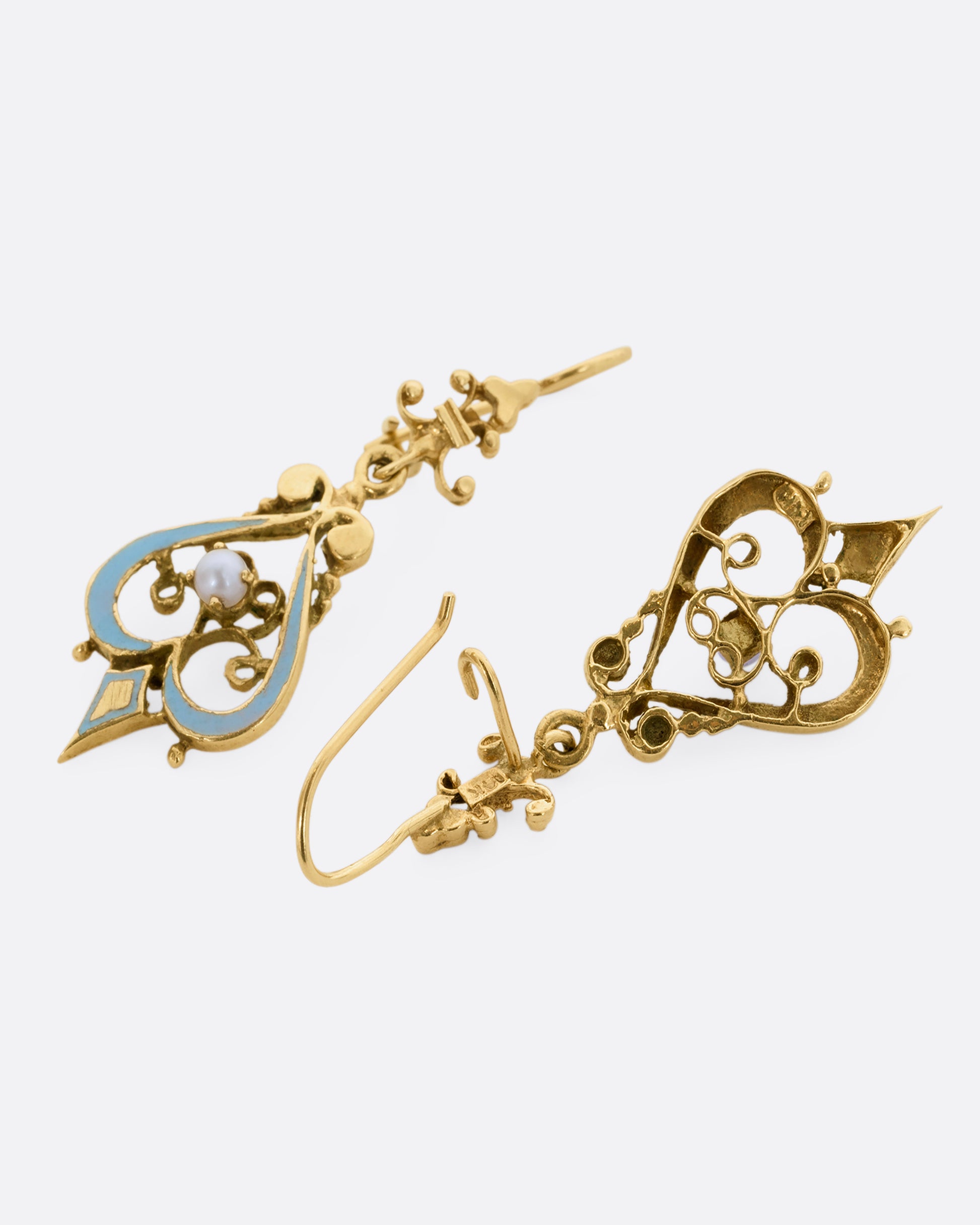 A pair of yellow gold filigree earrings with light blue enamel and pearls. Shown laying flat.