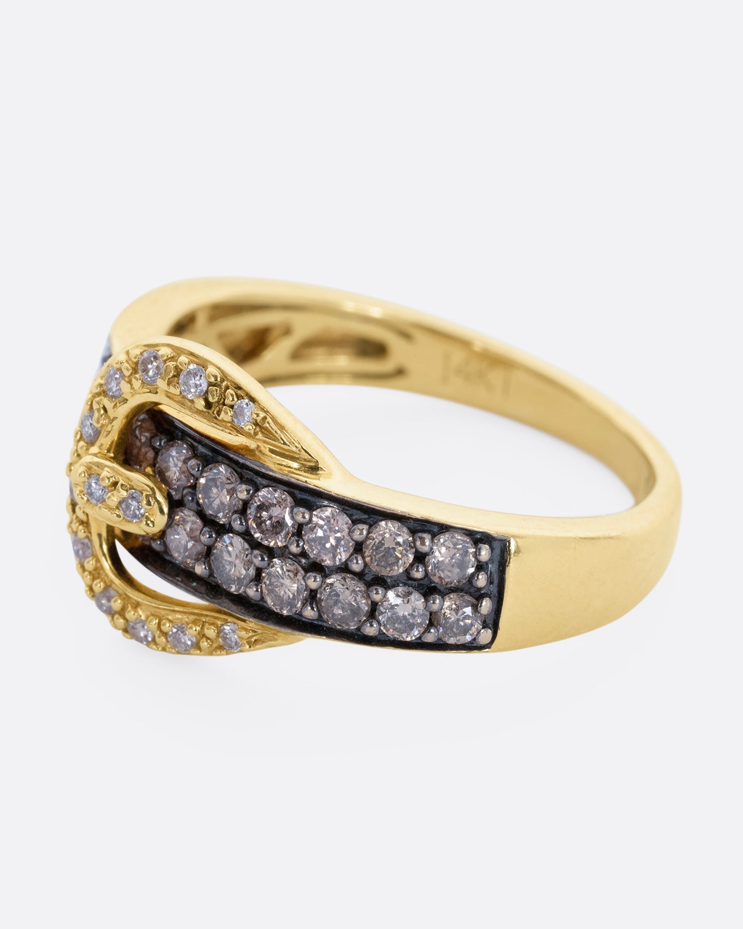 A diamond encrusted black and yellow gold belt buckle ring. View from the side.