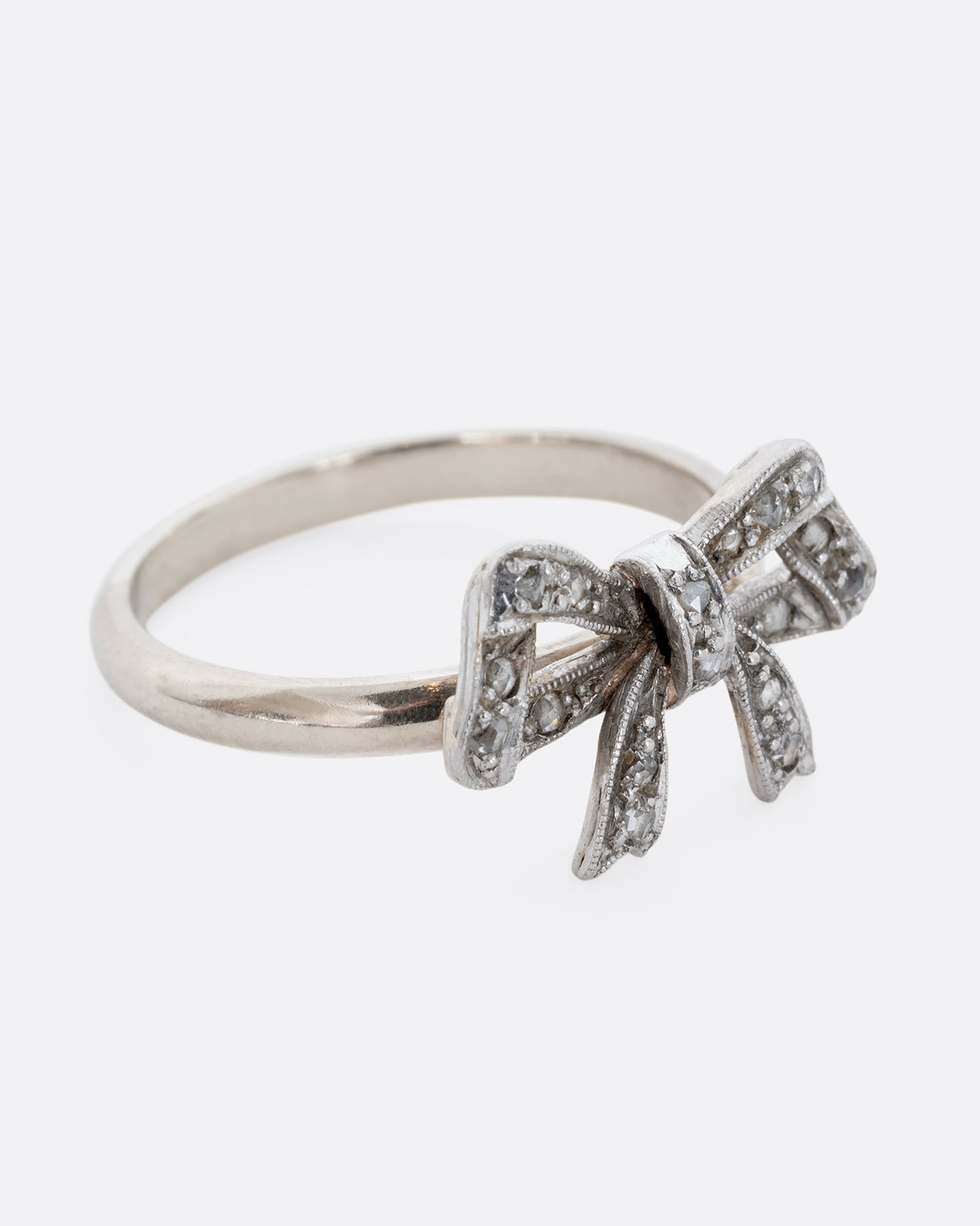 A white gold bow ring with diamonds. View from the side.