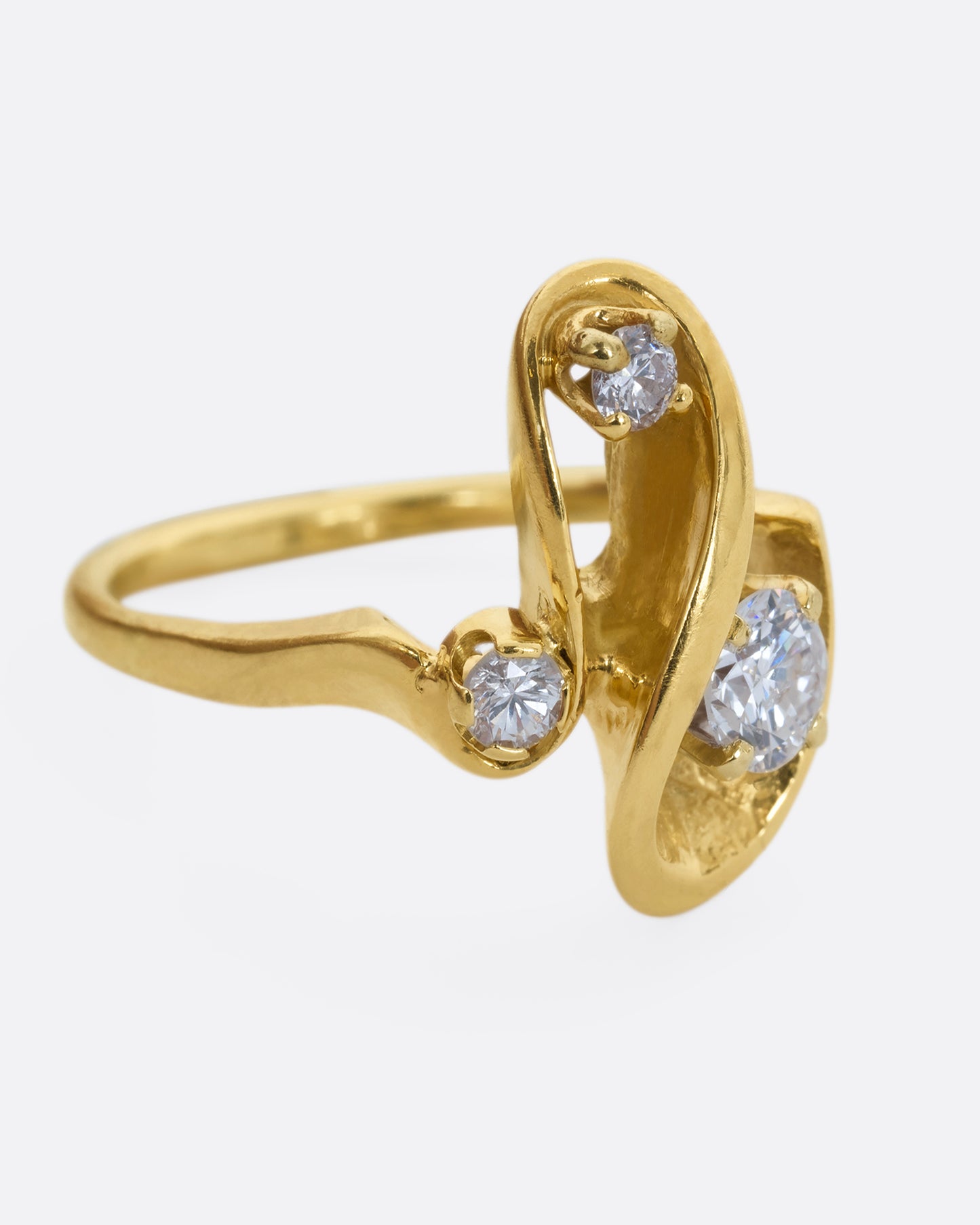 A yellow gold abstract swirl ring with three diamonds. View from the alternate side.