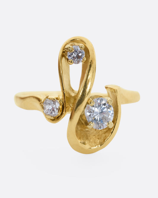 A yellow gold abstract swirl ring with three diamonds. View from the front.