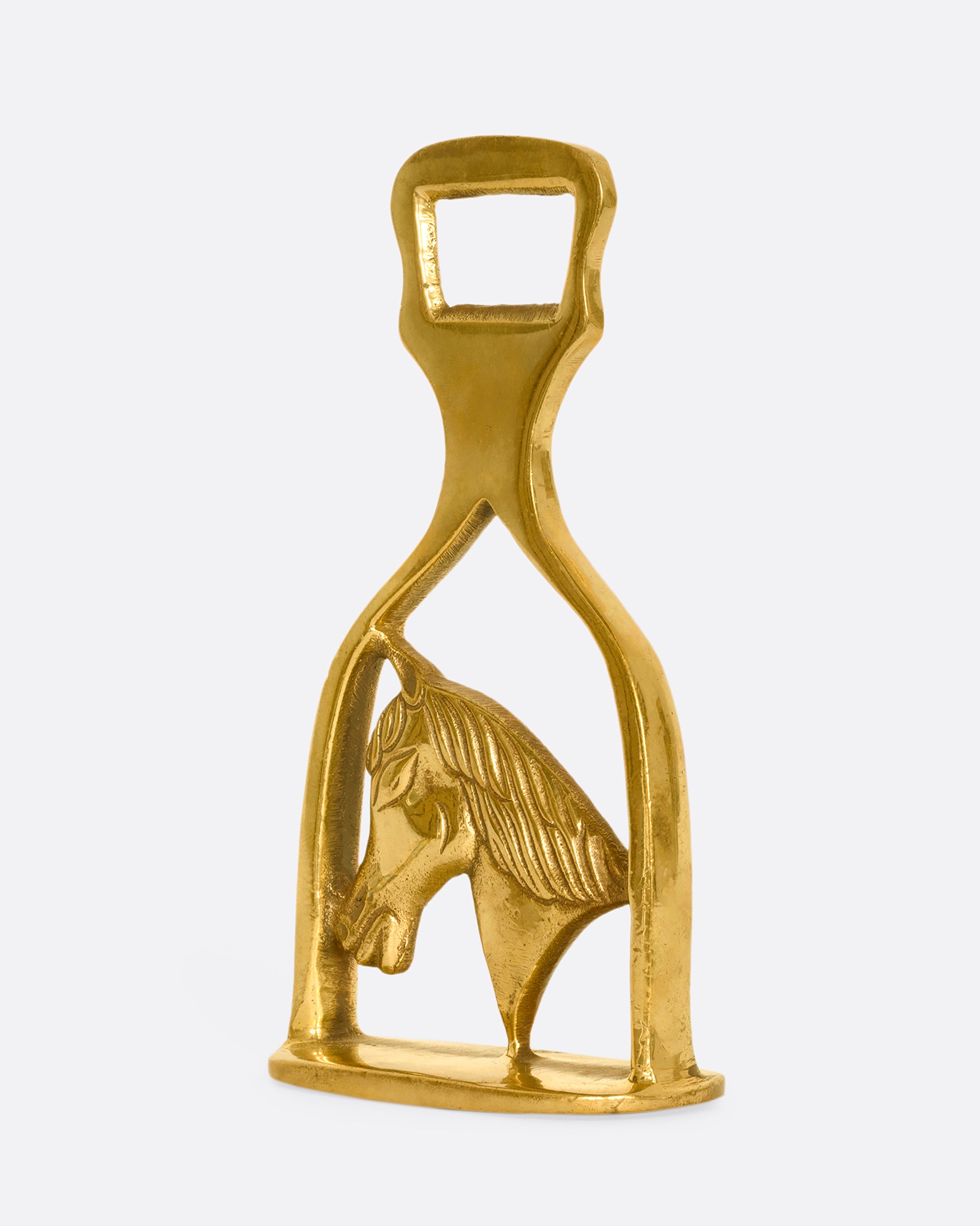 A brass horse bottle opener. Shown from the side.