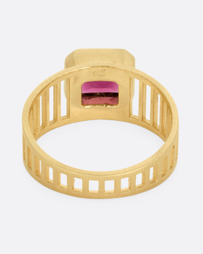 A yellow gold 'caged' band ring with a rhodolite garnet smolder, shown from the back.