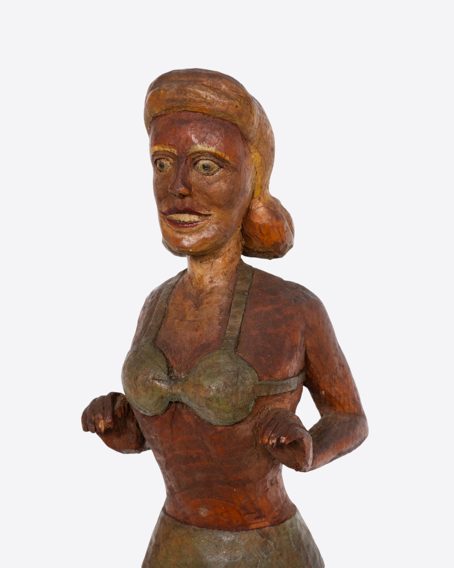 A hand carved wooden whimsy, a woman in a swimsuit standing on a ball. Shown up close from the side.