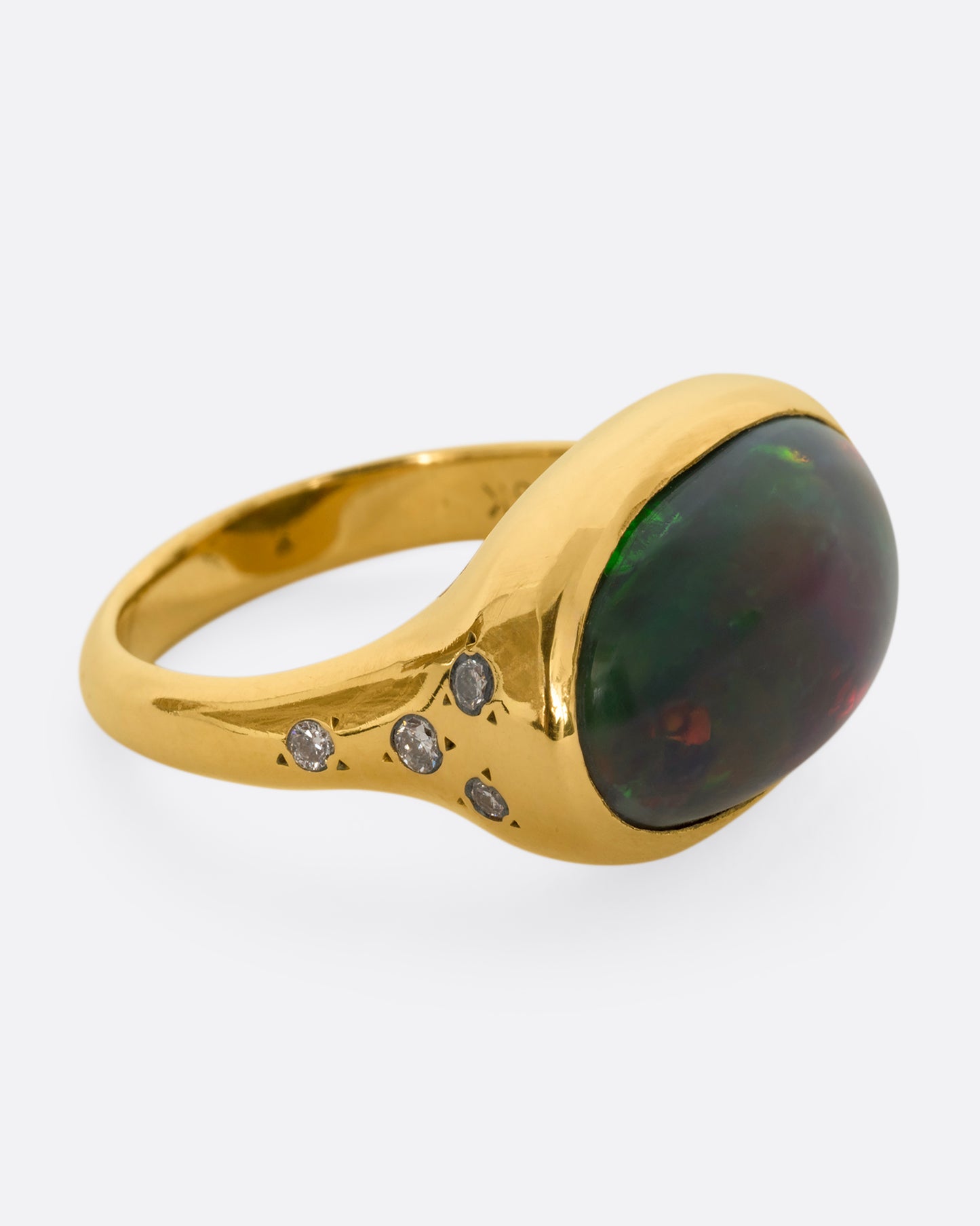 A yellow gold ring with a large oval opal at the center and diamonds on either shoulder. View from the alternate side.