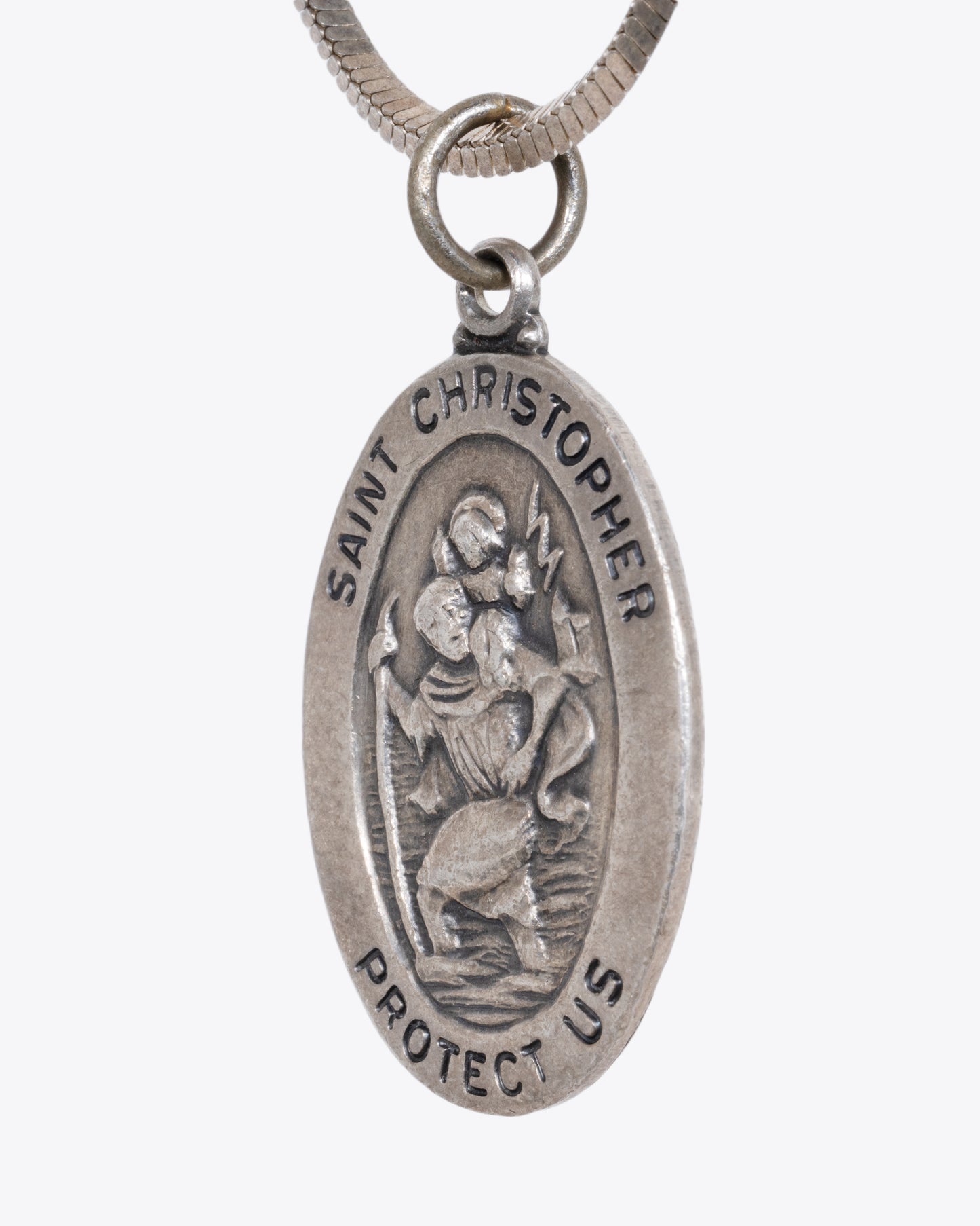 A sterling silver St. Christopher pendant hanging from a snake chain. View close up from the side.