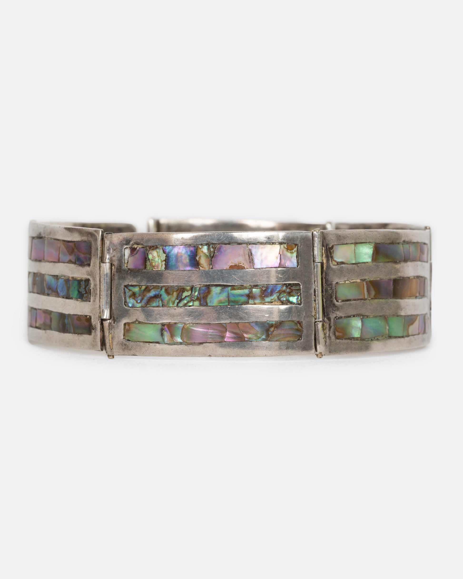 A sterling silver bracelet with rectangular links containing three abalone stations on each. View from the front, closed.